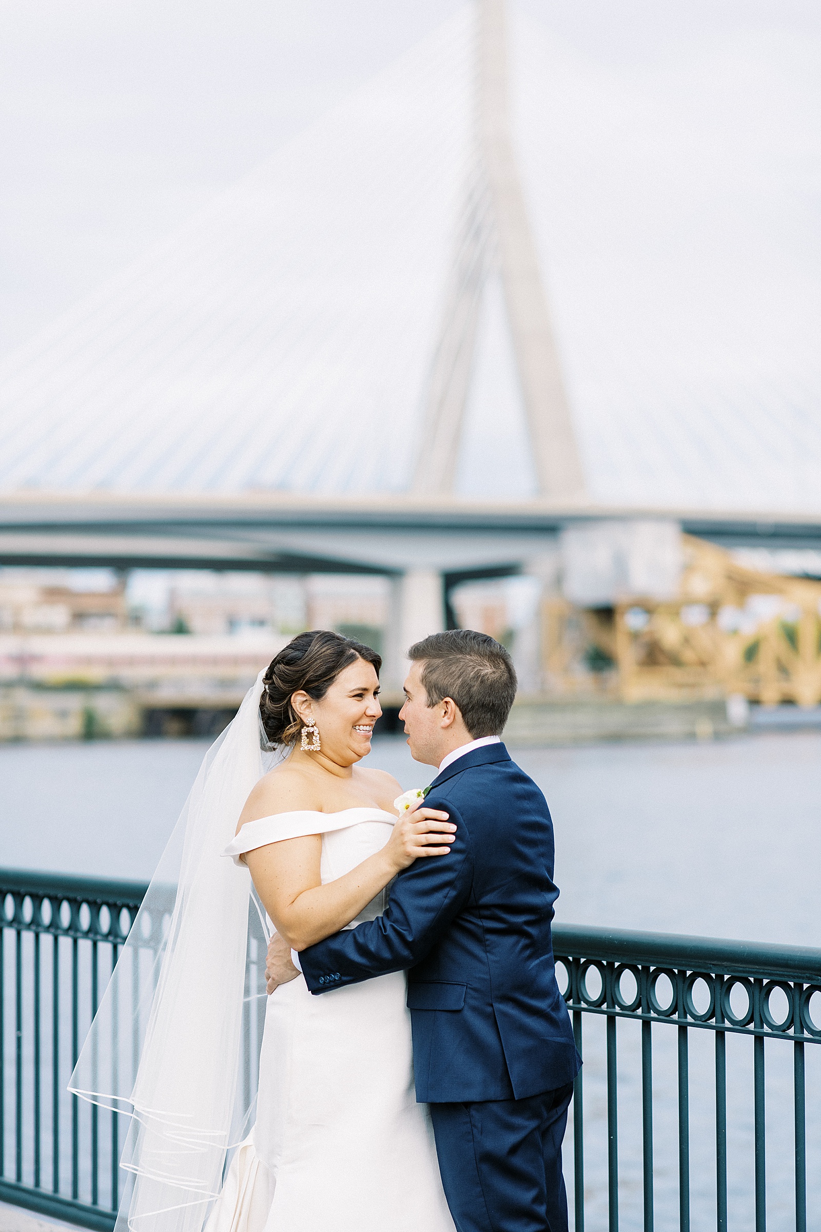 Bride and groom embracing in front of a bridge by New York wedding photographer