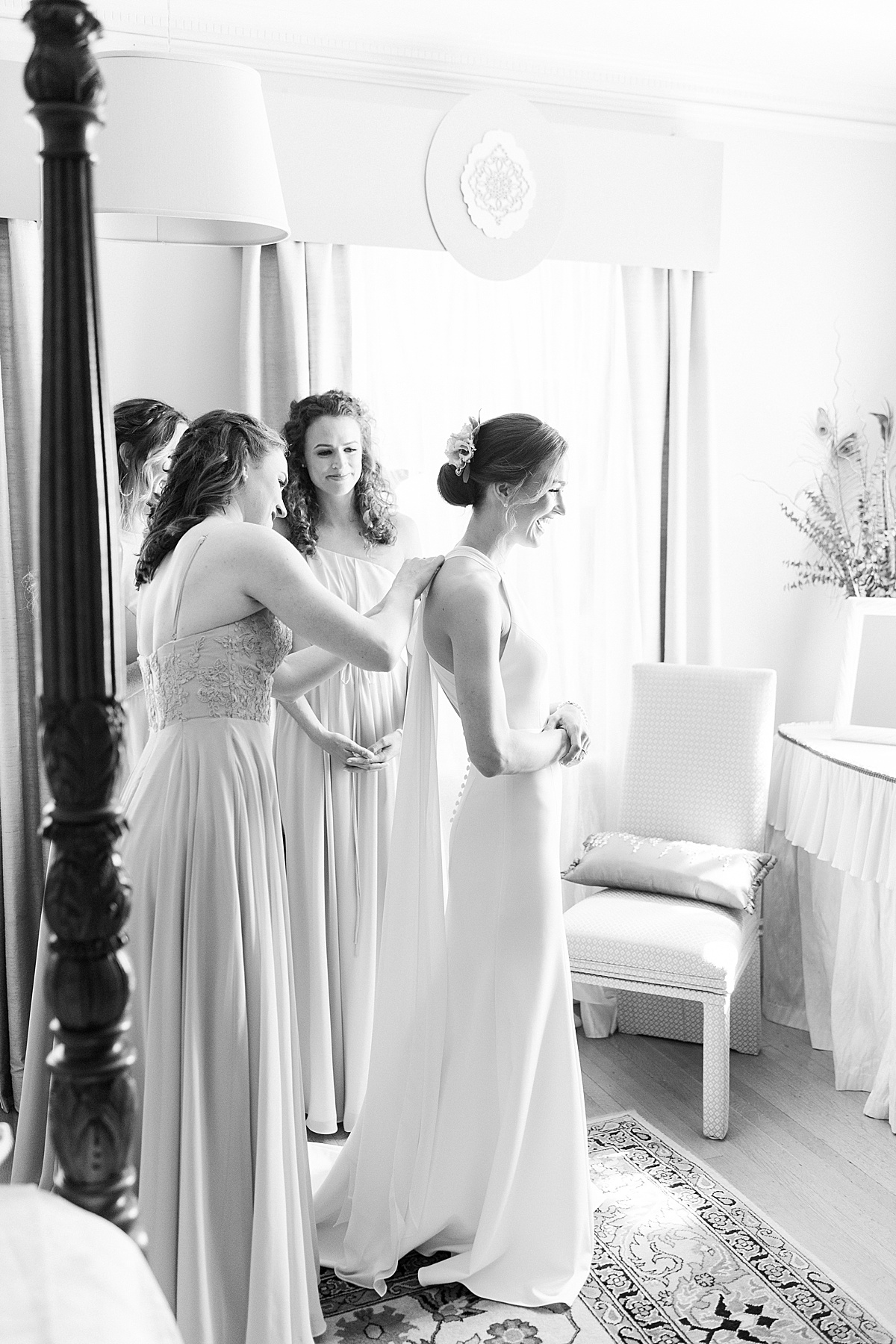 bridesmaids help bride in svelte modern gown get ready at charming hotel before Glen Magna farms wedding