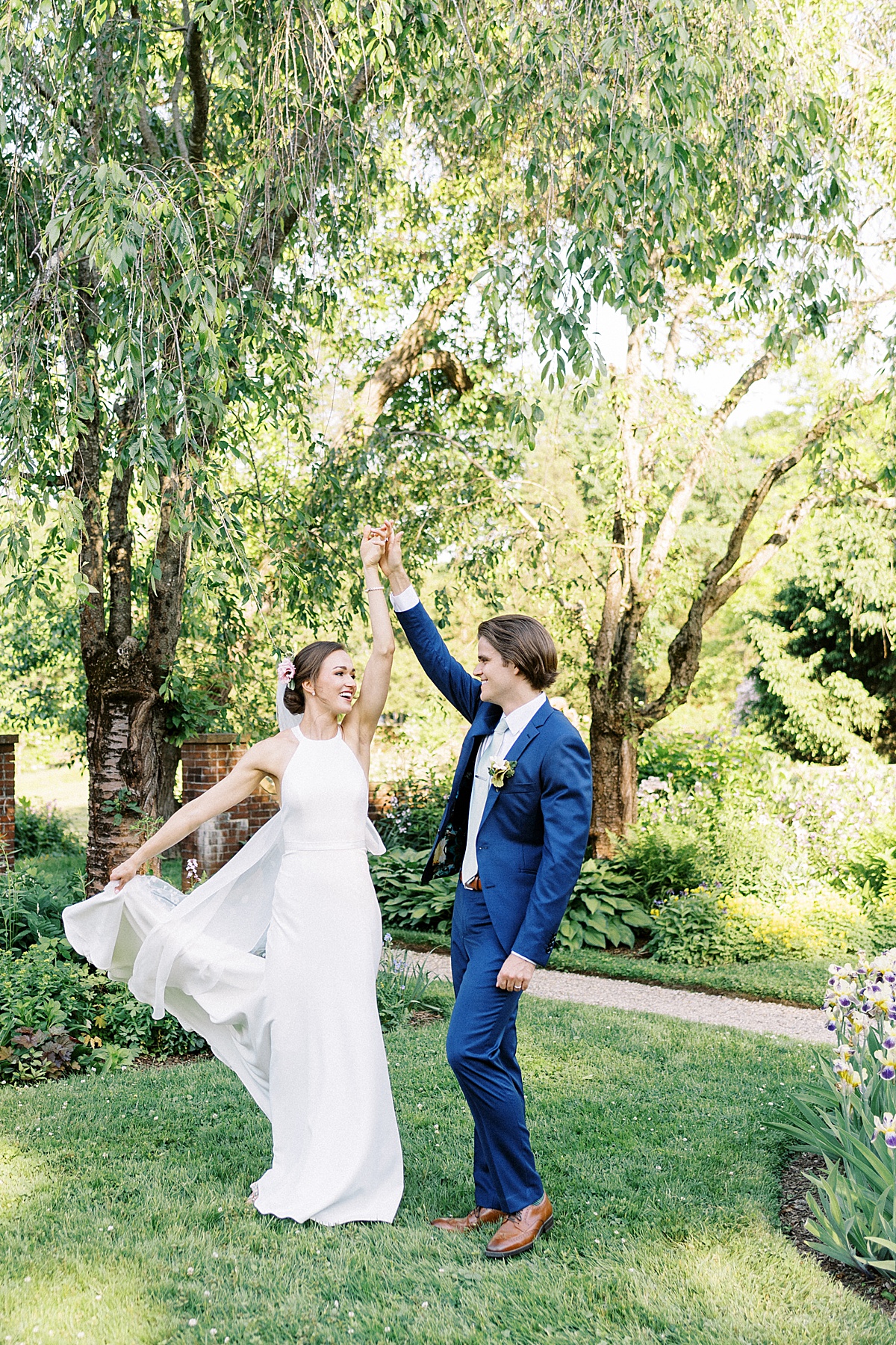 groom in blue suit twirls bride in modern simple gown before ceremony shot by Lynne Reznick Photography