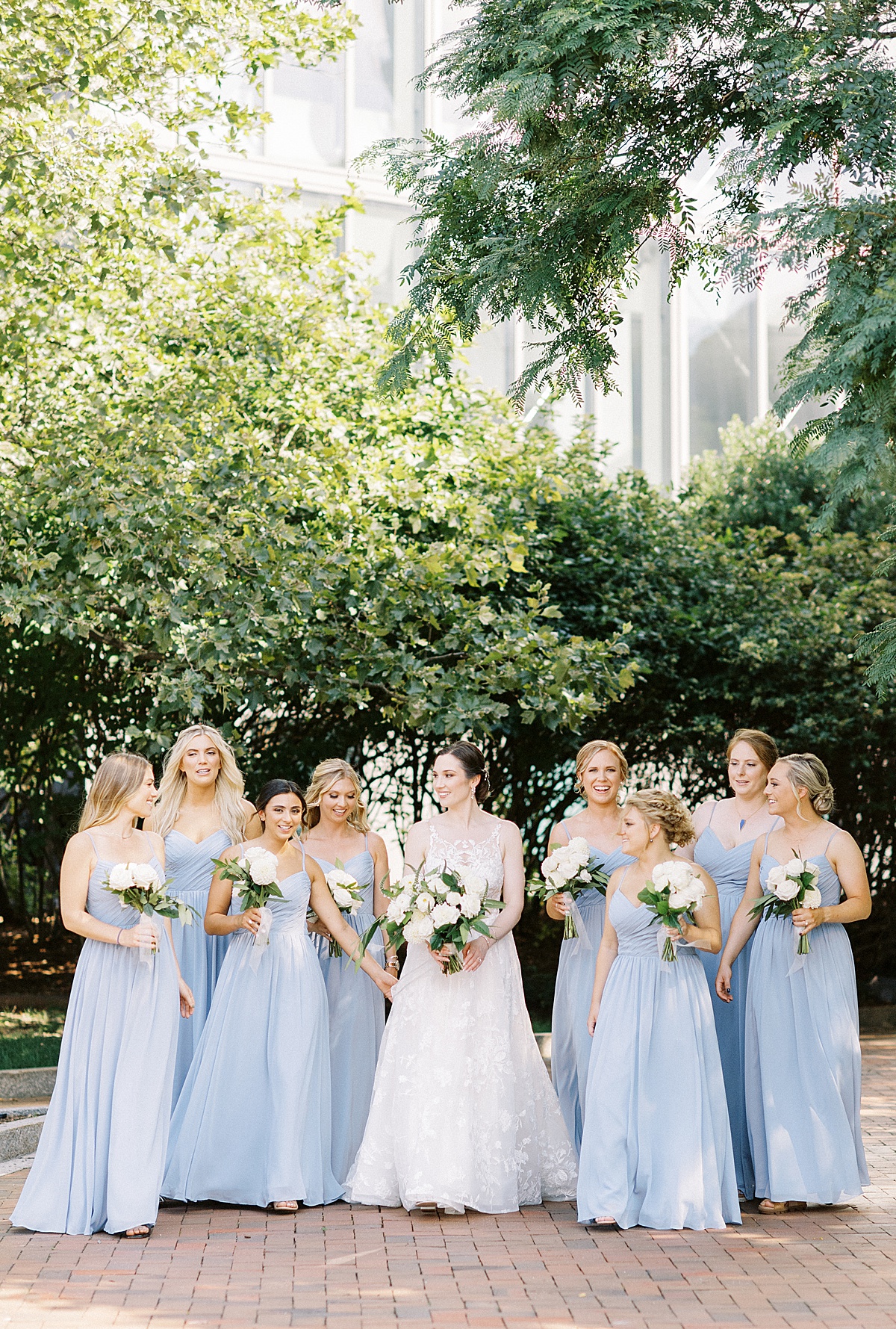 bride and bridal party in pale blue chiffon gowns carry white bouquets before nautical oceanview wedding