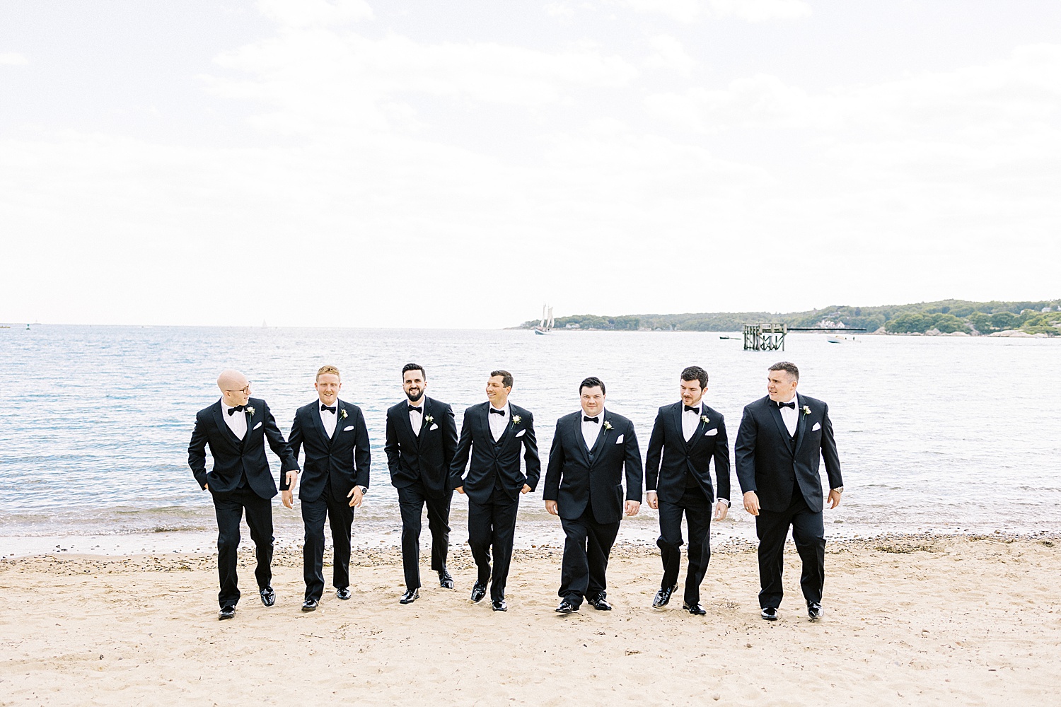 Groomsmen walking on beach by Massachusetts wedding photographer