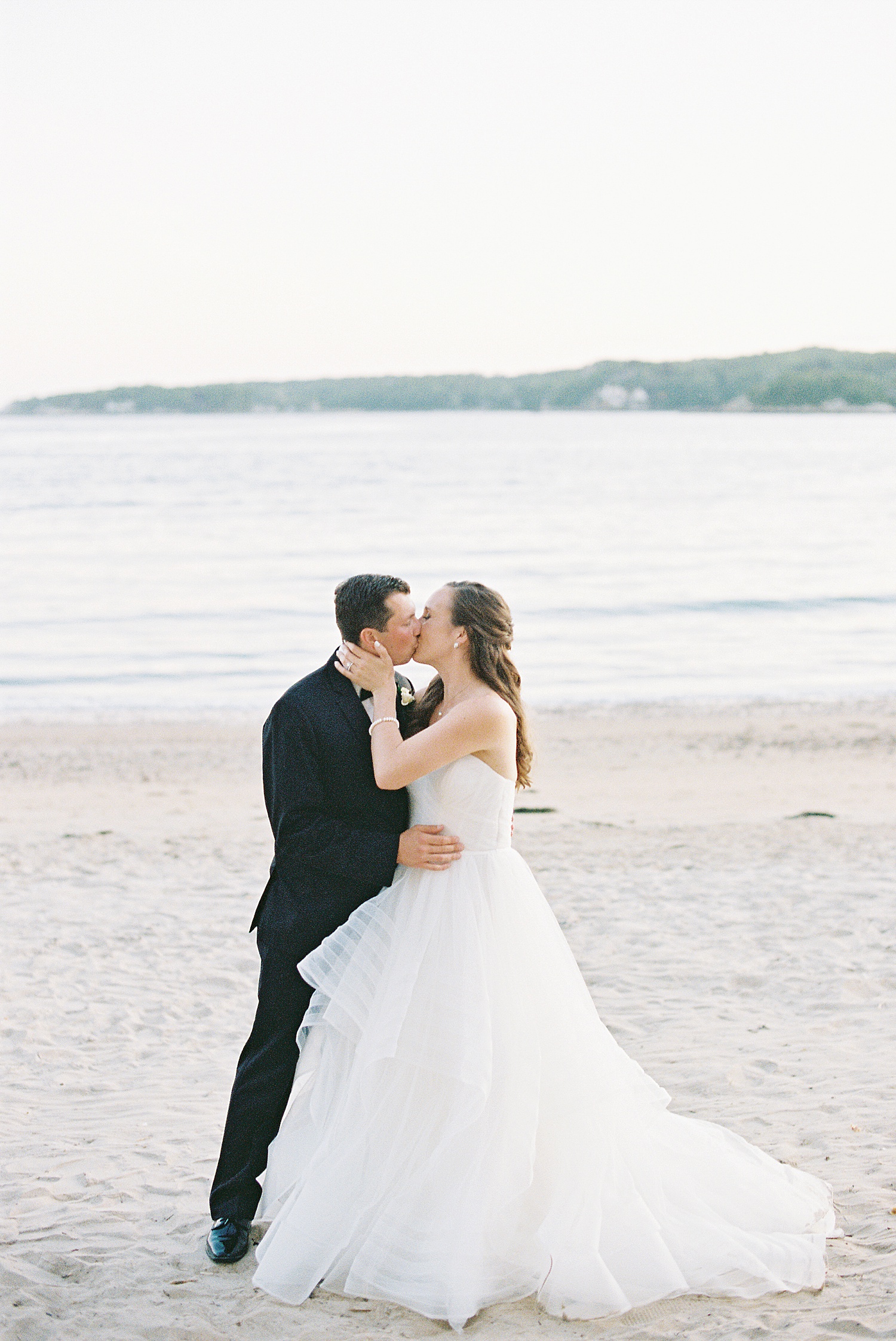 Newlyweds share a kiss on the beach by Massachusetts wedding photographer