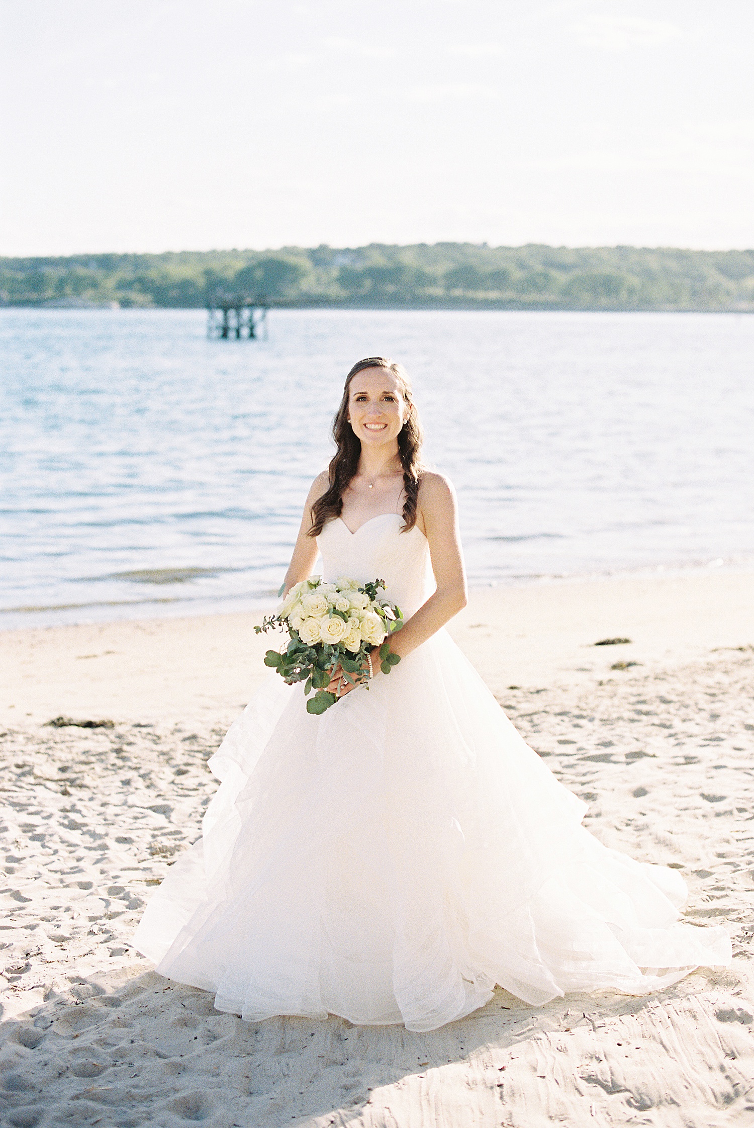 Bride standing on beach with her flowers by Lynne Reznick photography