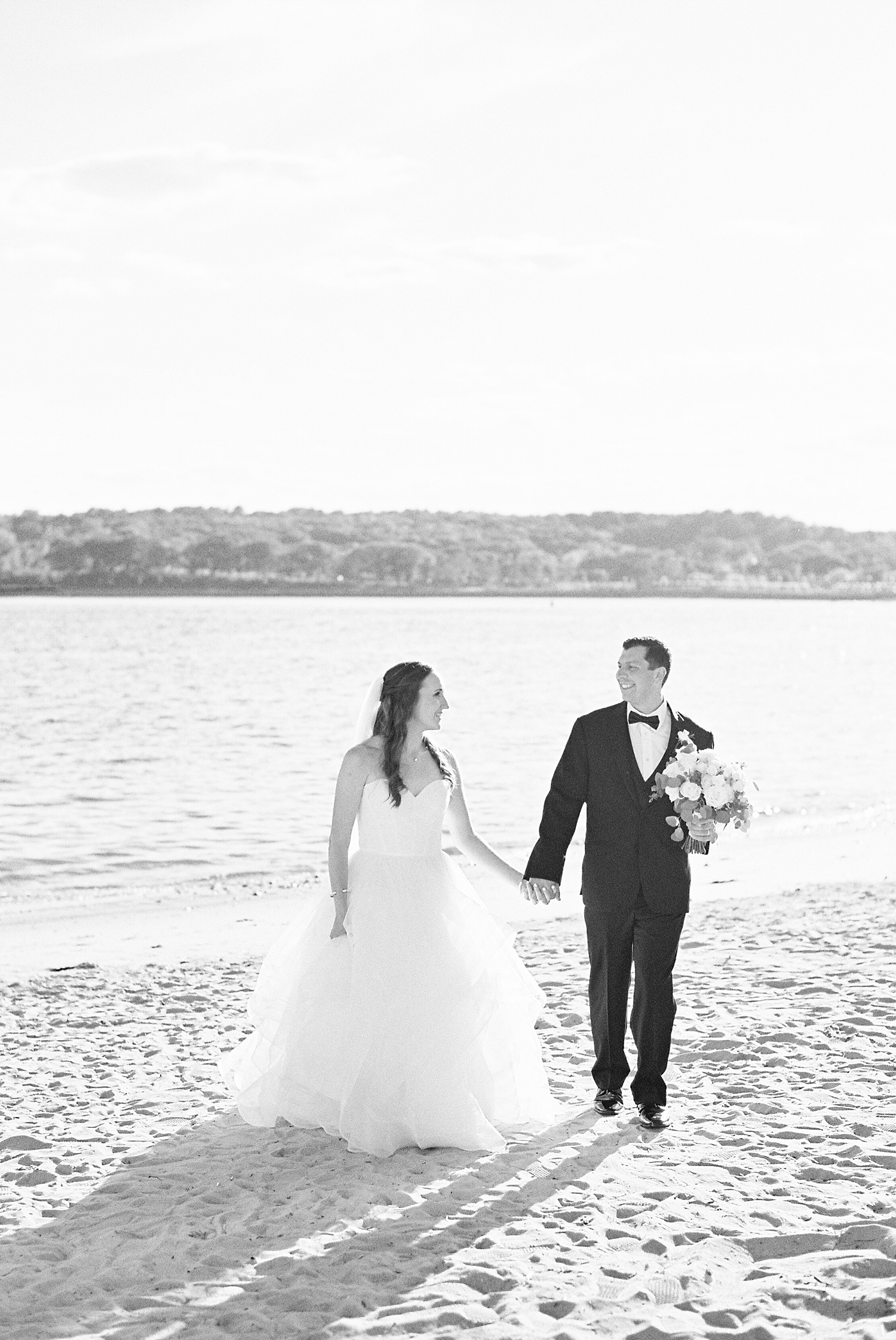 Bride and groom walking on the beach by Massachusetts wedding photographer