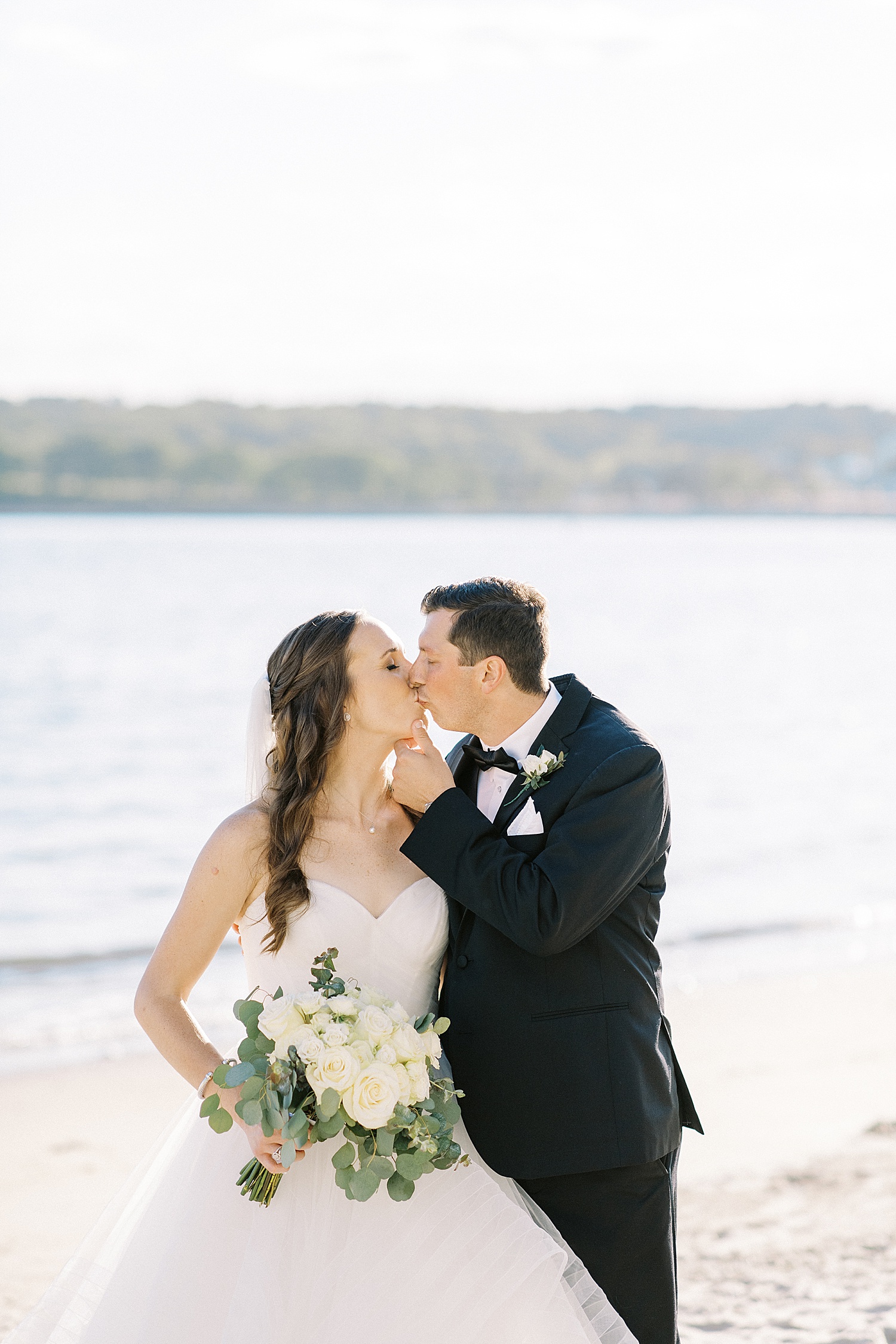 Newlyweds share a kiss at beach at Beauport Hotel