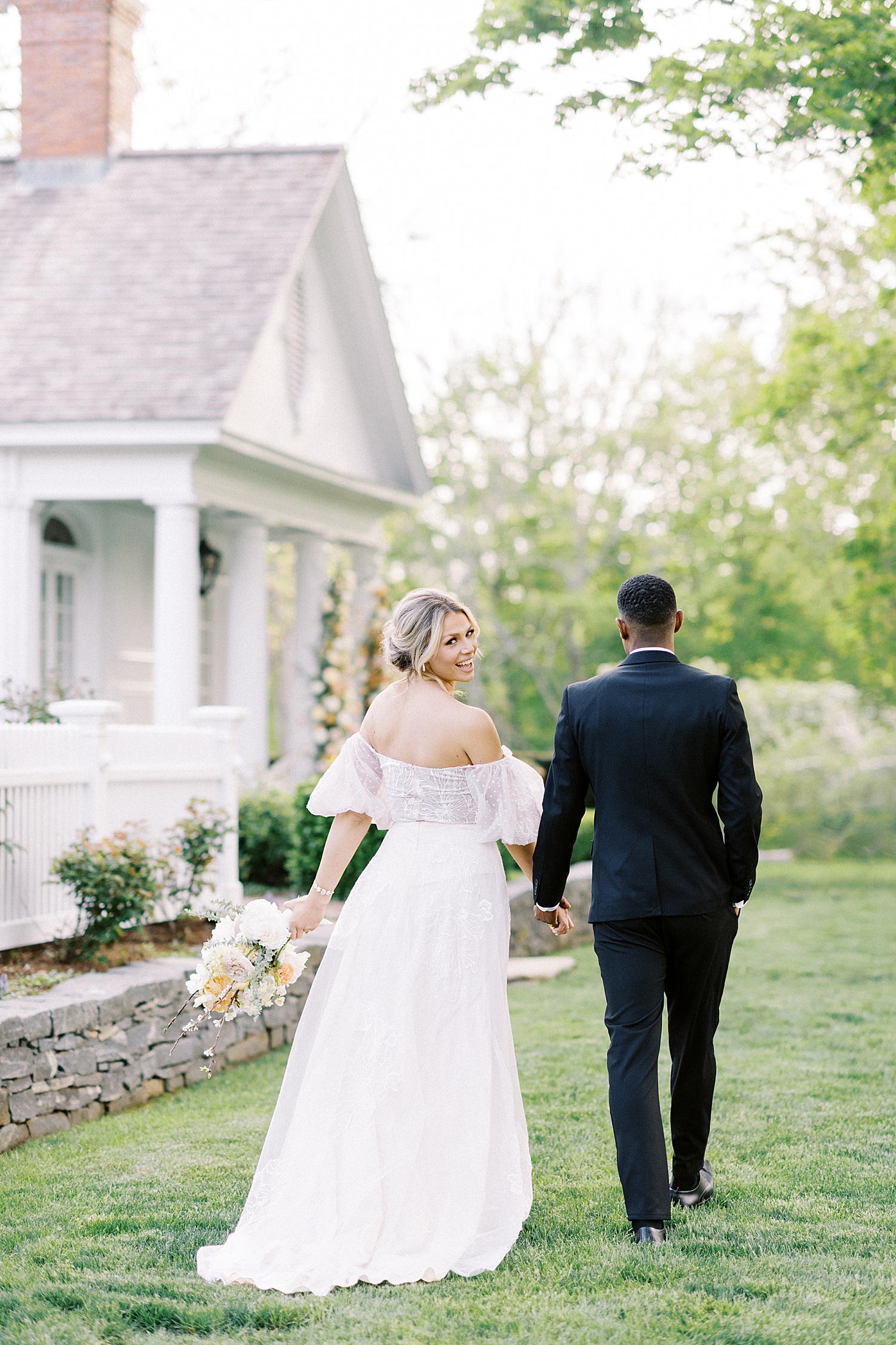 bride and groom walking through a garden by Lynne Reznick Photographer