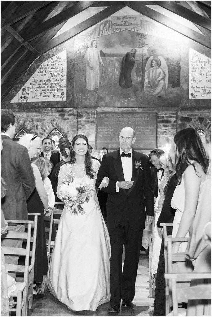 black and white of bride processing down the aisle with her dad