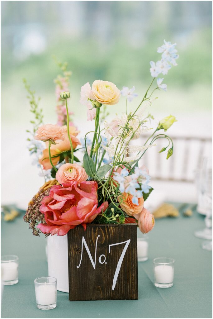 pink and peach floral centerpieces with wood block table numbers for tented catskills wedding