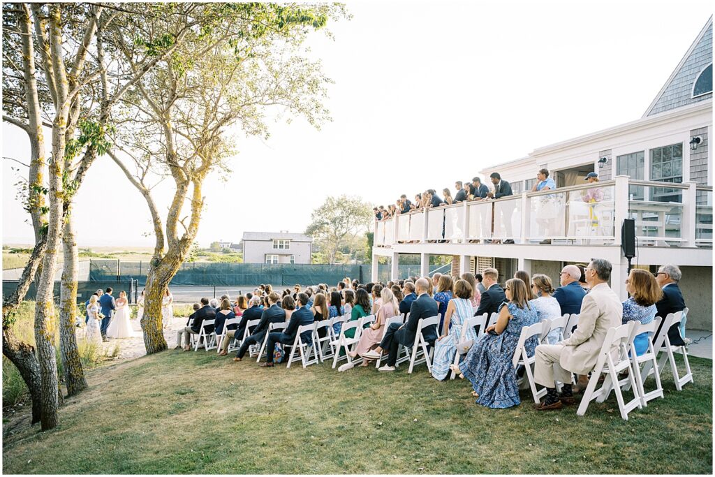 guests sit on hillside lawn for wedding ceremony in Chatham