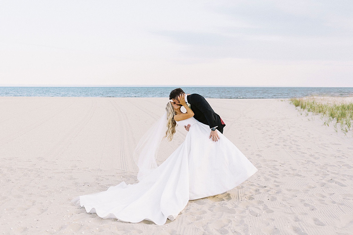 groom dipping his bride on the beach captured by a Cape Cod Wedding Photographer at Wychmere Beach Club