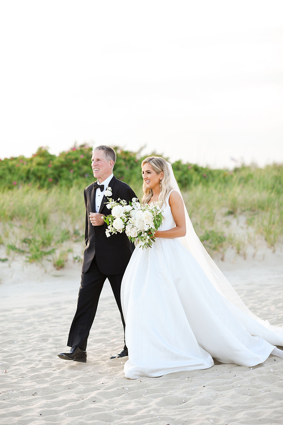 bride walking down aisle with dad and a Cape Cod Wedding Photographer takes photos