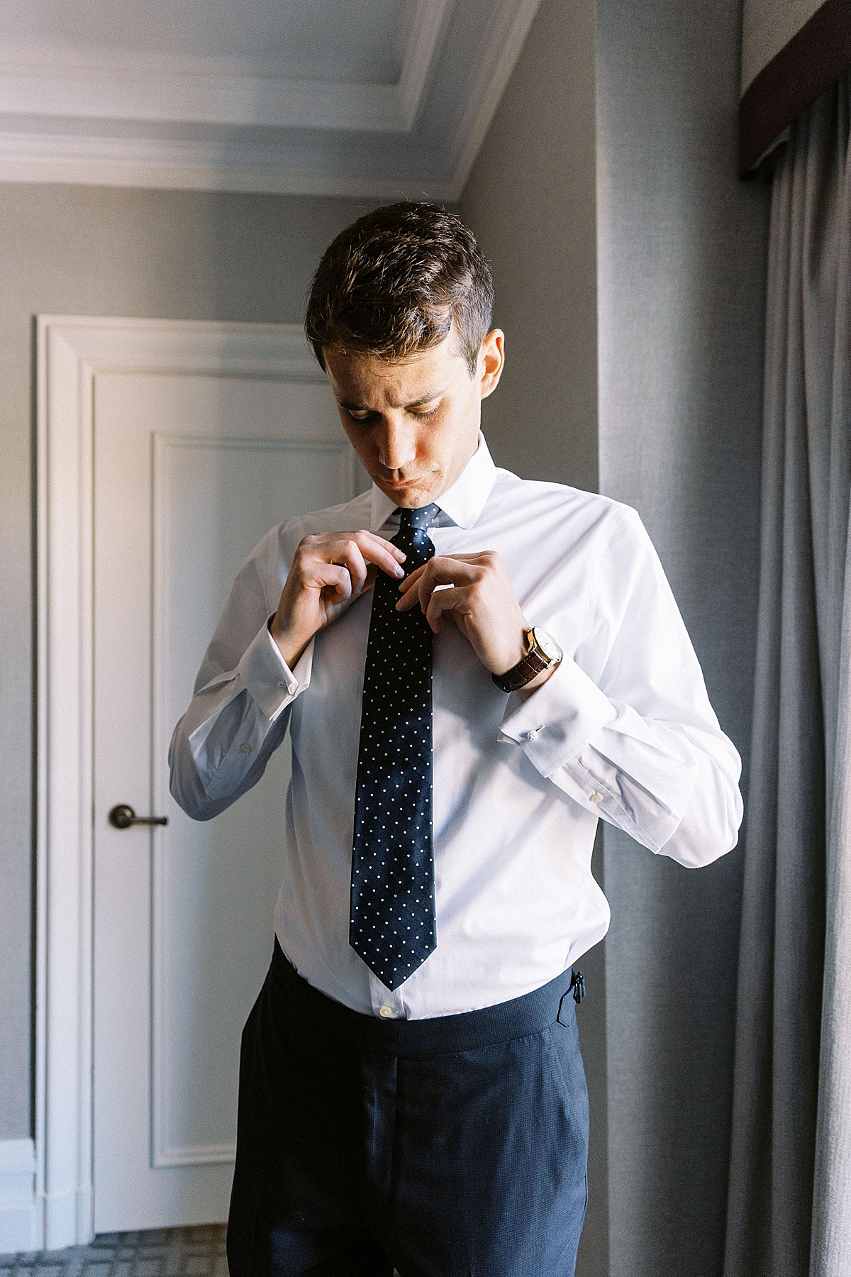 groom fixing tie in his Fairmont Copley Suite