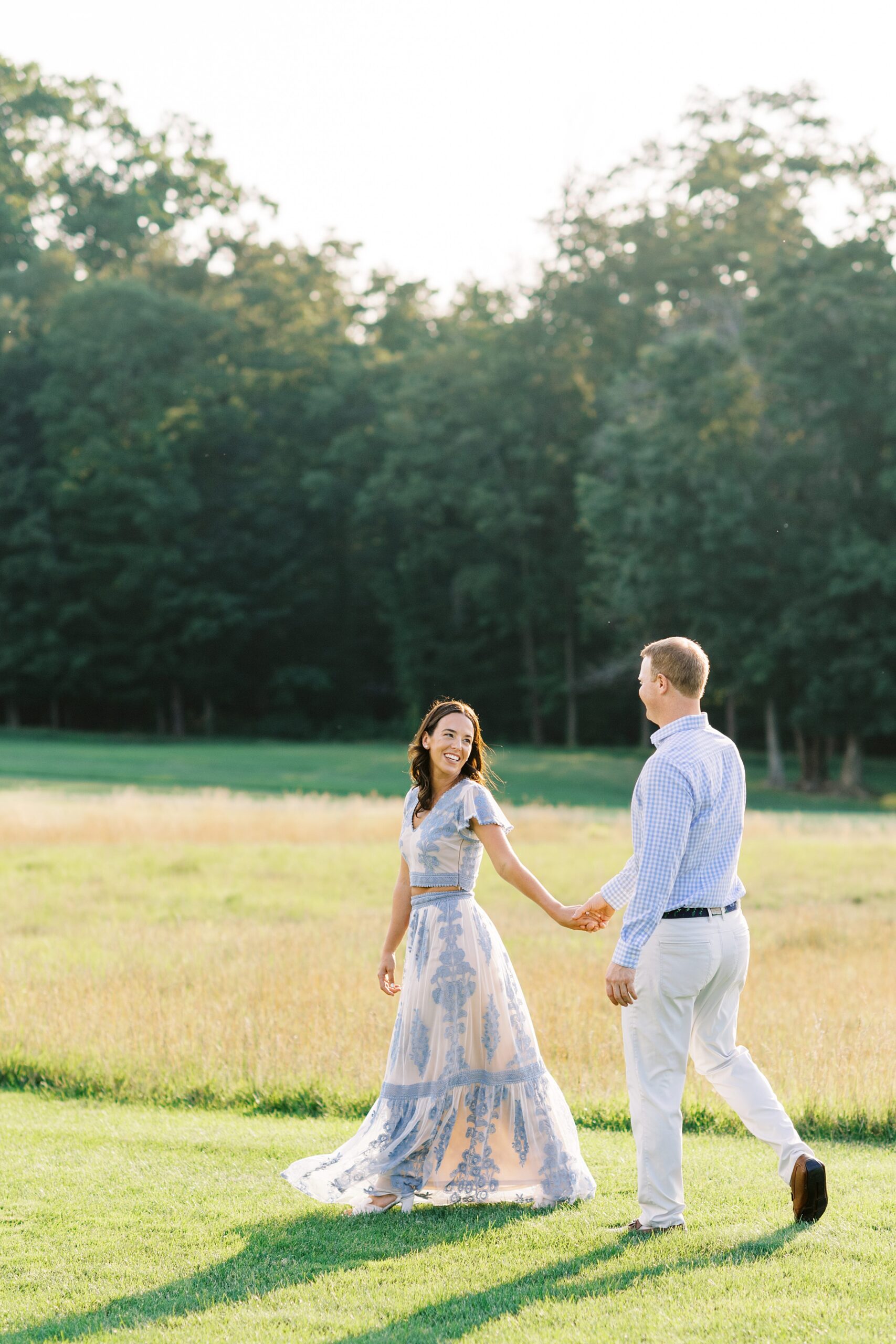 coouple walking along fairway in french blue outfits during golf course engagement session in NY