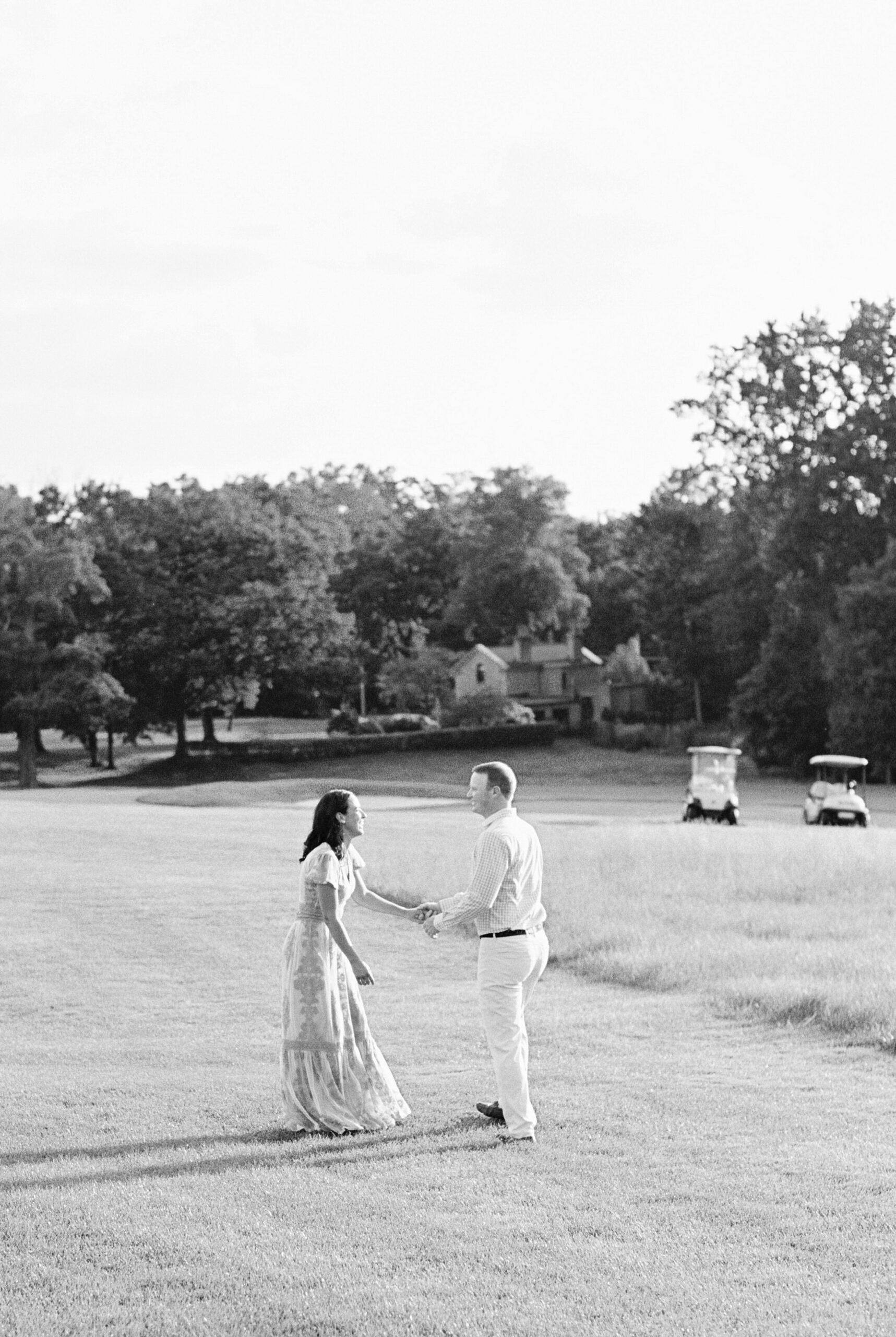black and white of couple during country club engagement session on golf course