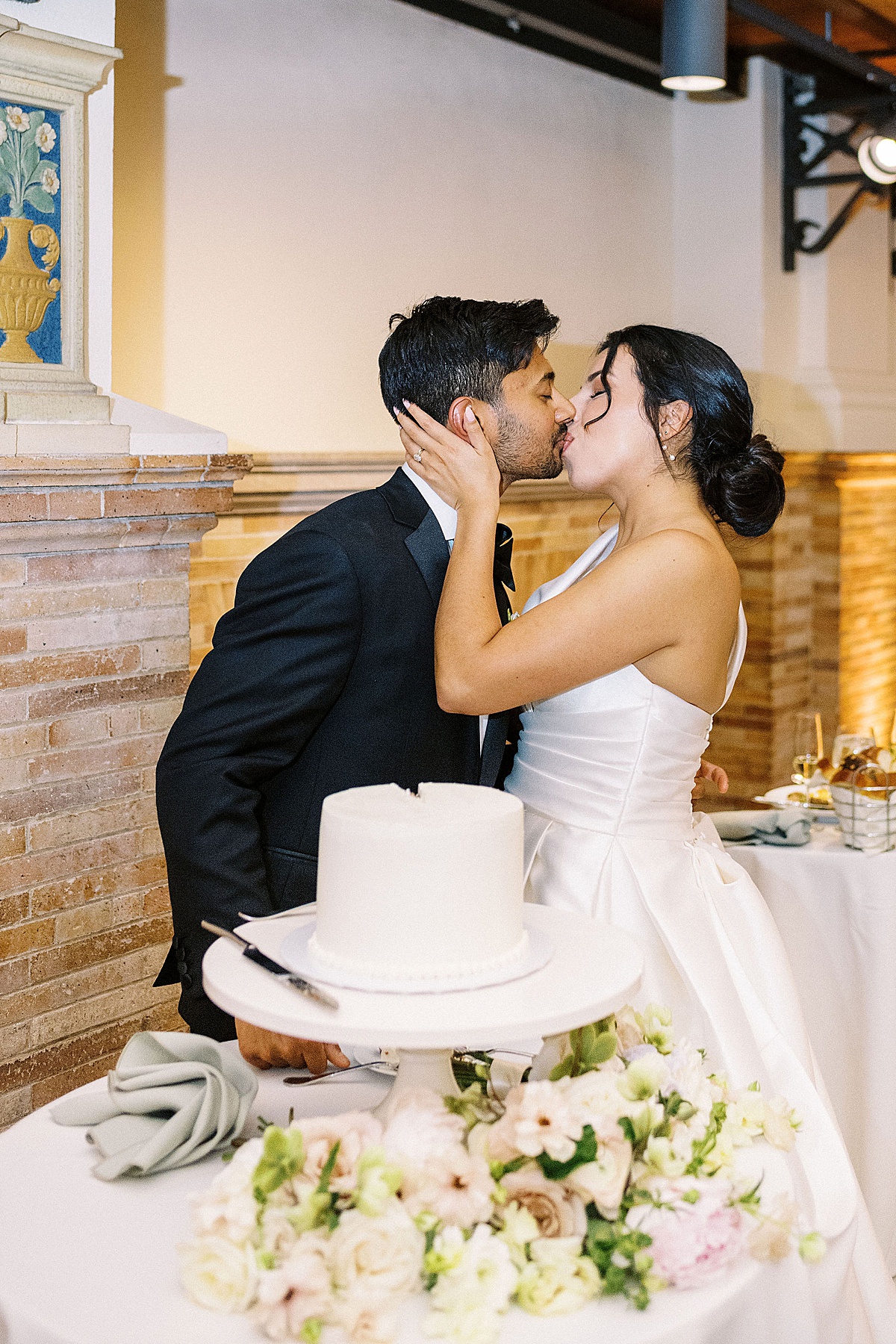 bride and groom kissing in front of cake captured by Lynne Reznick Photography