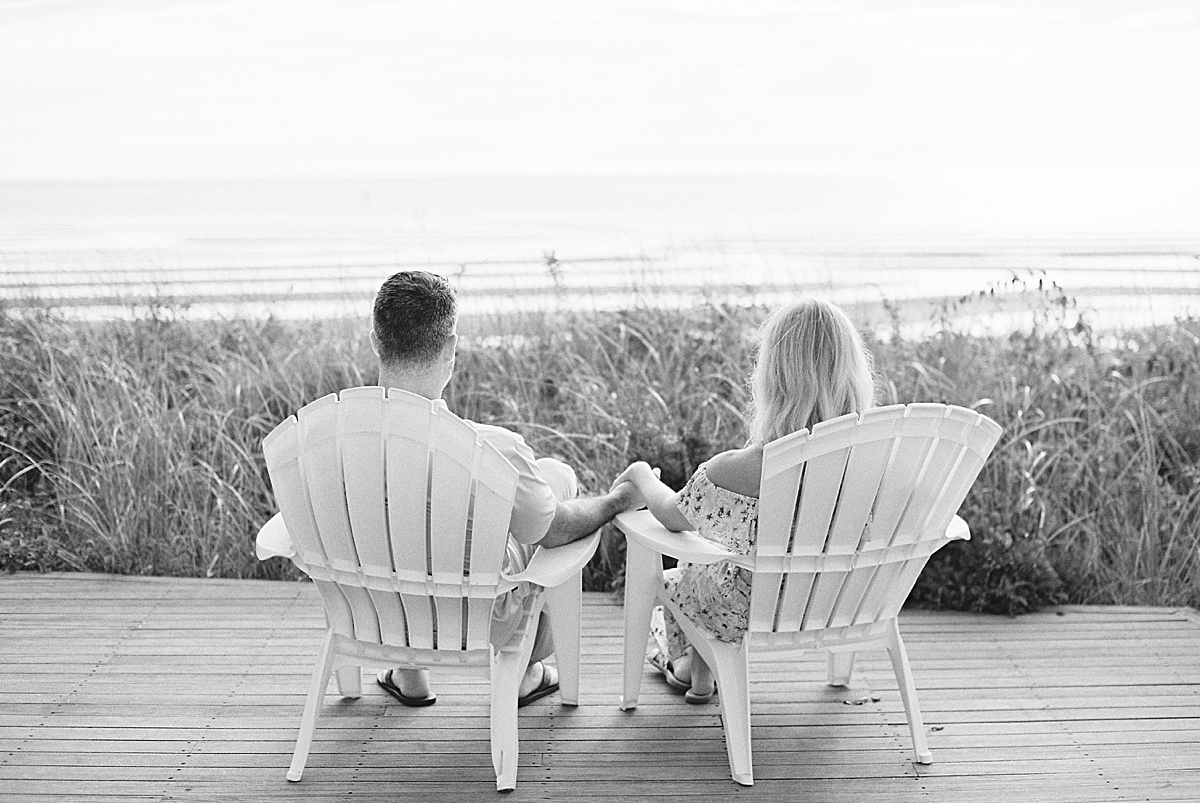 man and women holding hands sitting on lawn chairs during Cape Cod engagement