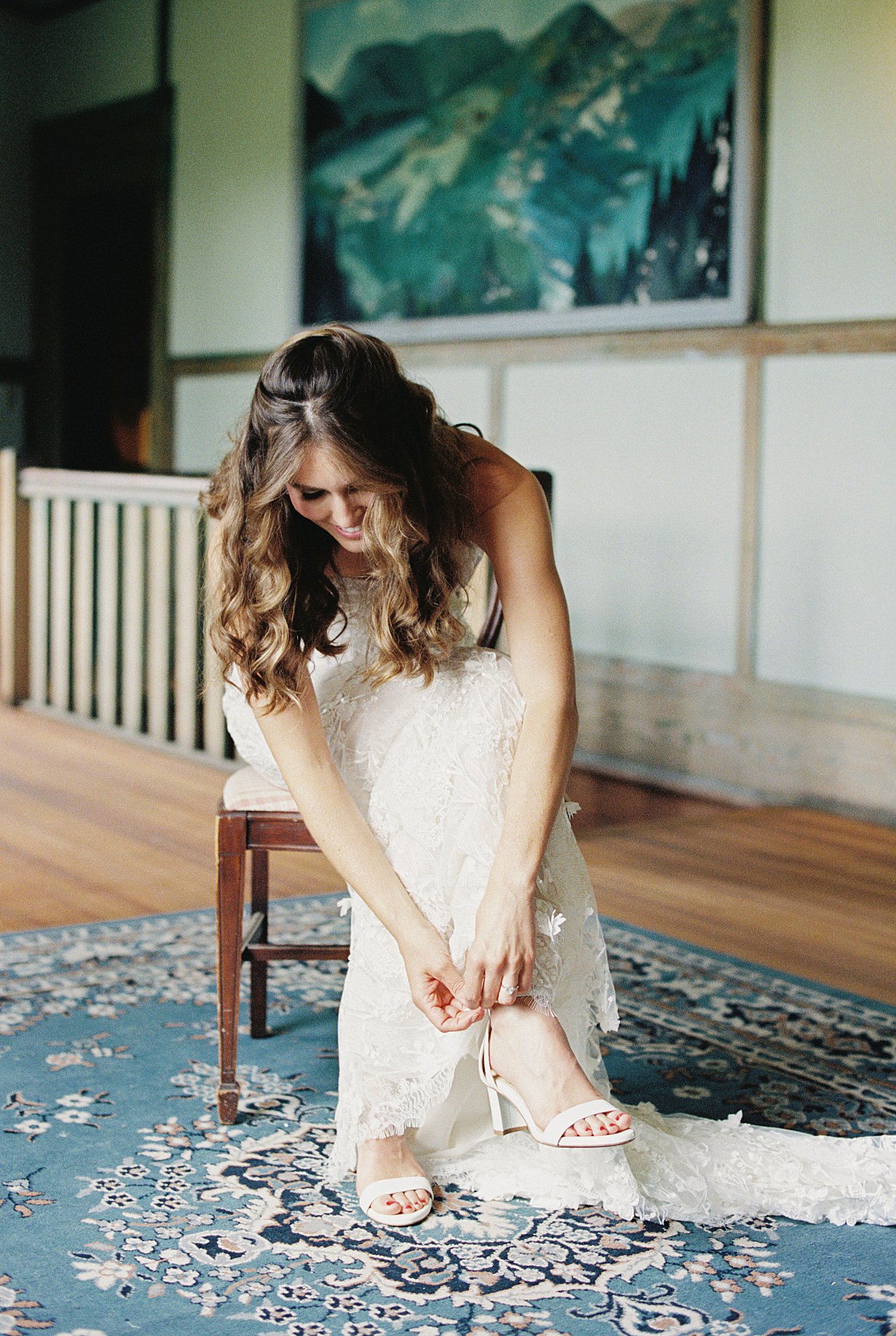 bride puts shoes on as she sits in chair by Cape Cod wedding photographer