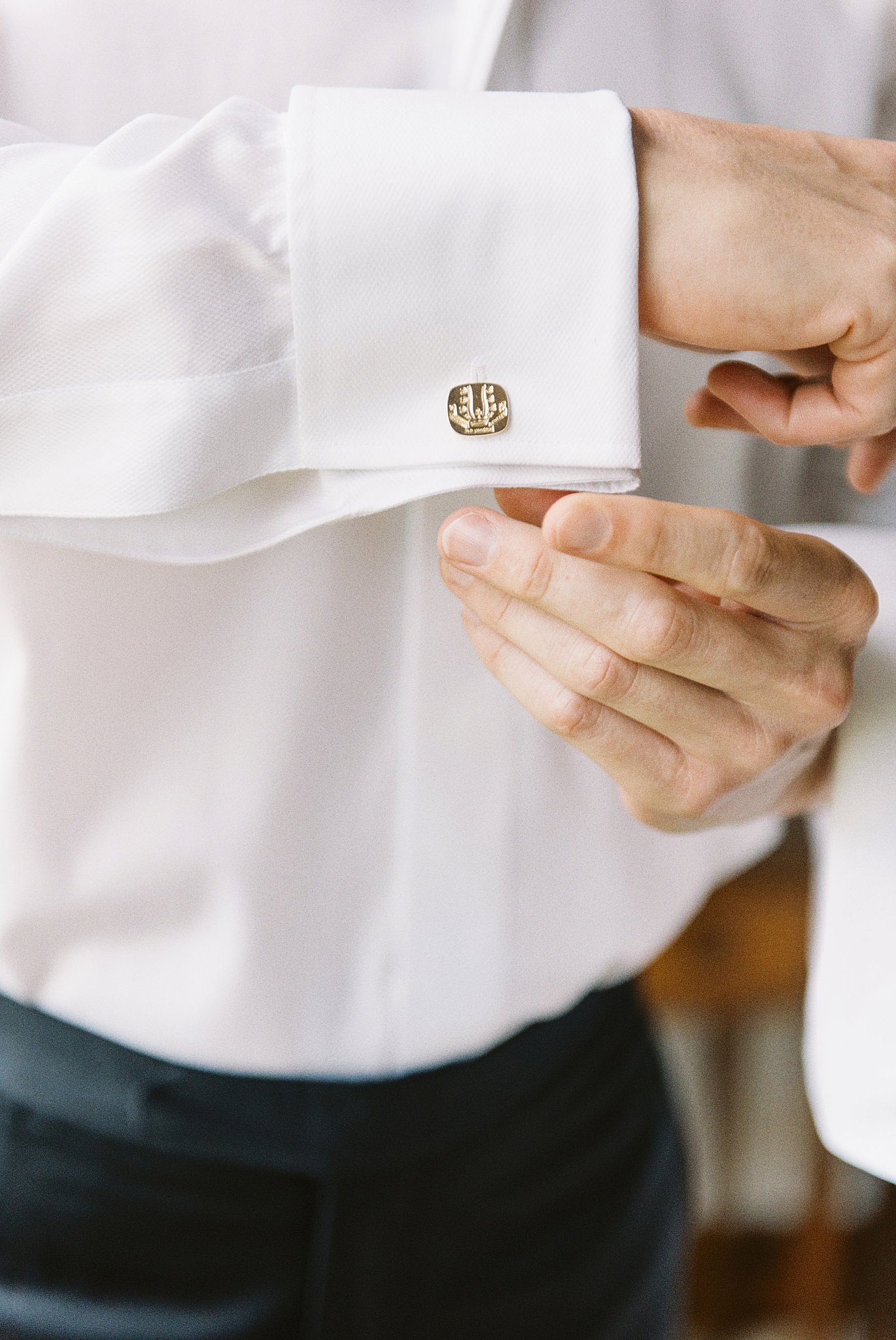 groom adjusts his cufflinks by Lynne Reznick Photography 