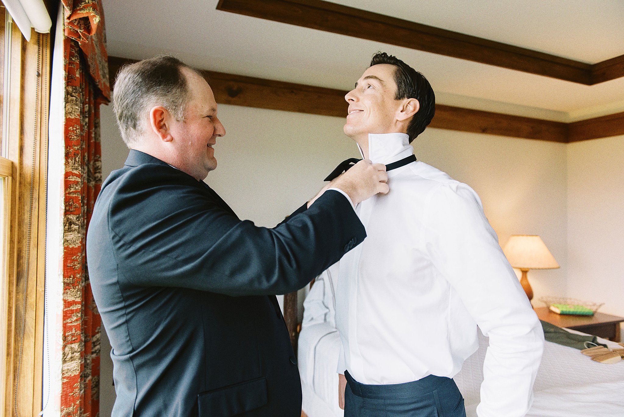 groomsman helps groom adjust bowtie at Onteora Club