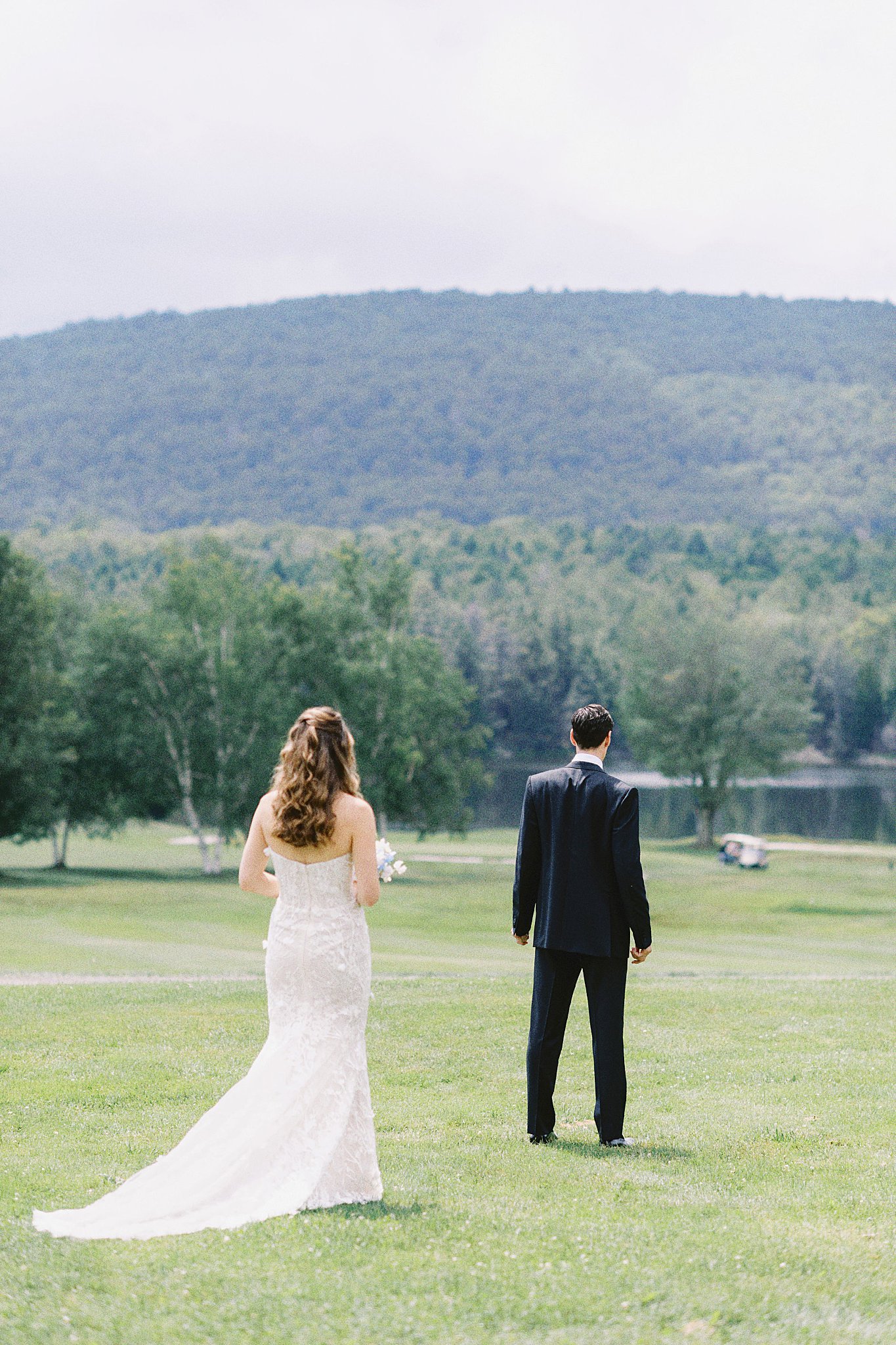 bride walks up to groom for first look near lake at Onteora Club