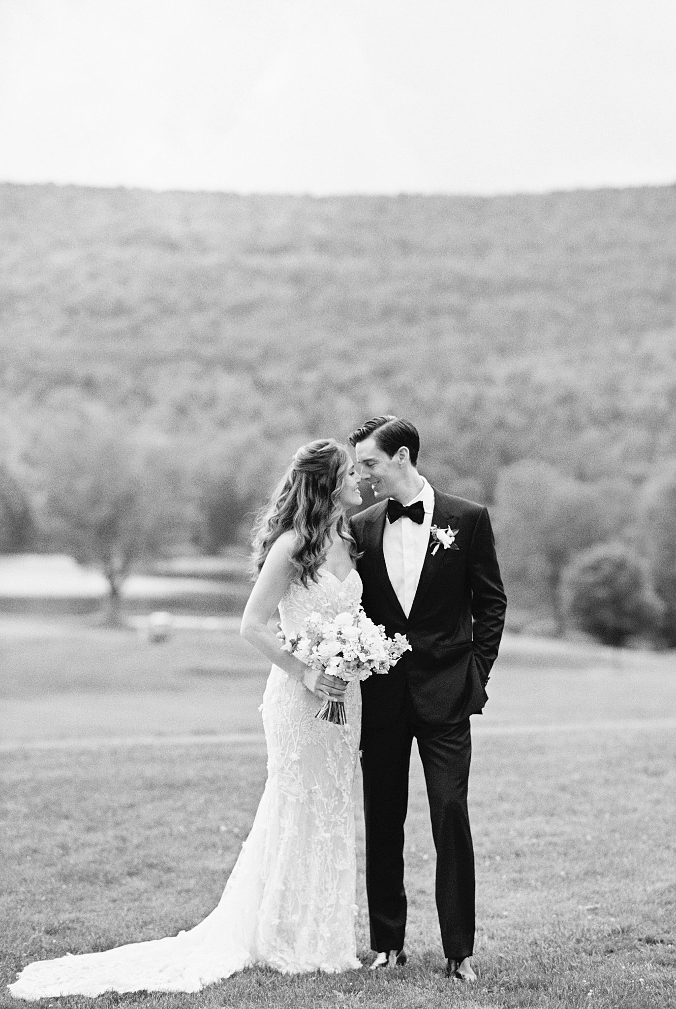 couple touches noses as they smile and she holds bridal florals by Catskills NY wedding photographer