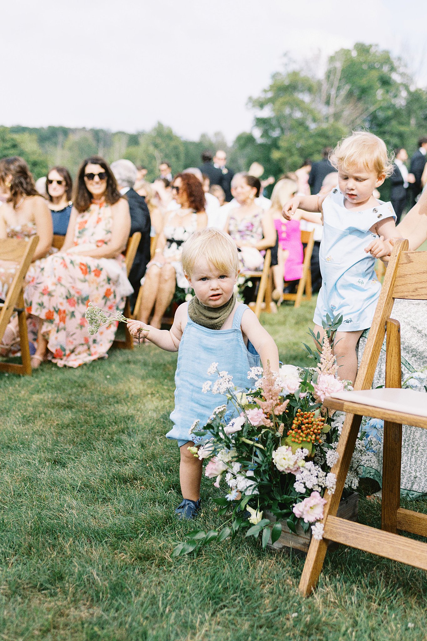 toddlers play with florals at ceremony by Catskills wedding photographer