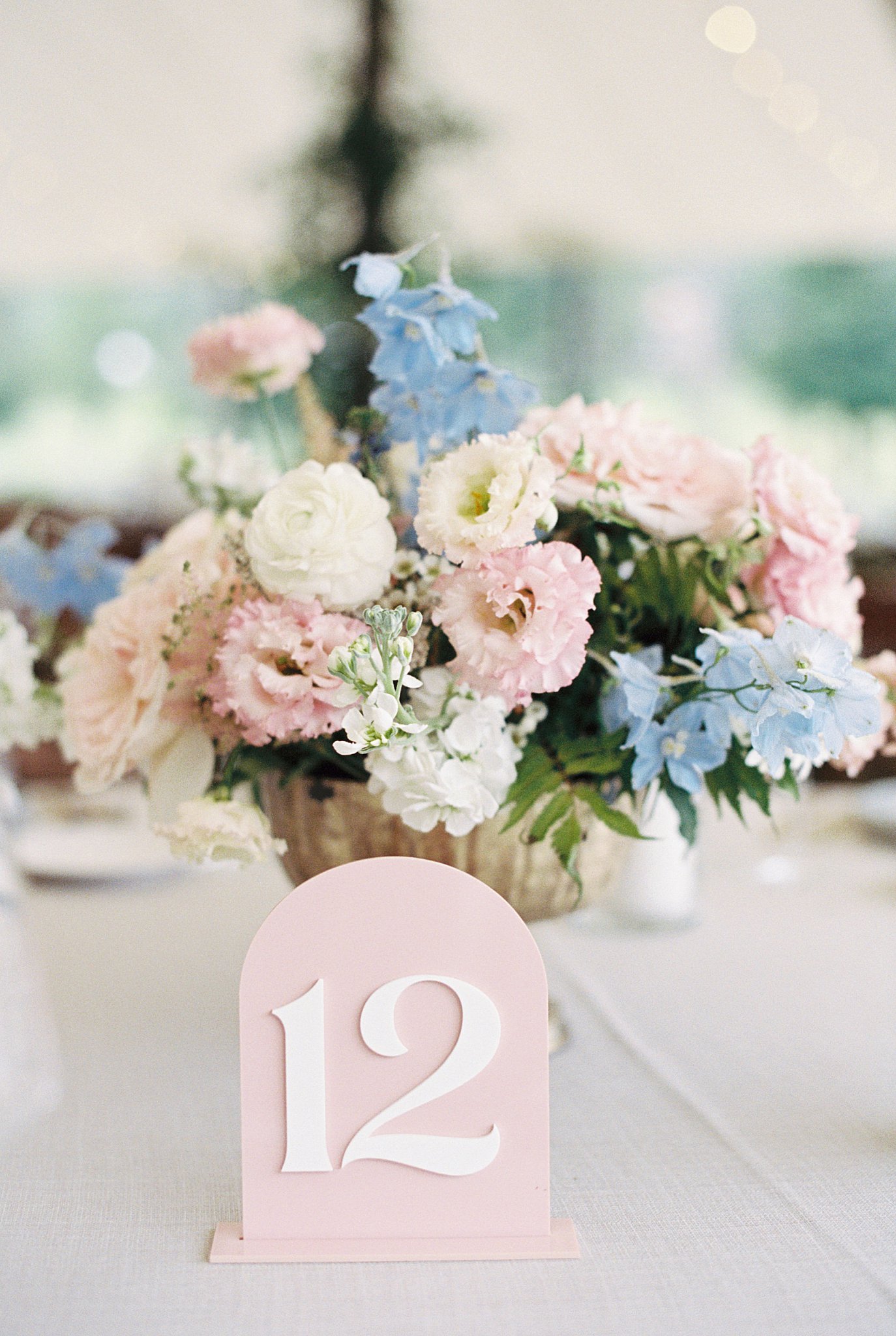 pastel floral centerpiece sits next to blush pink table number at Onteora Club 