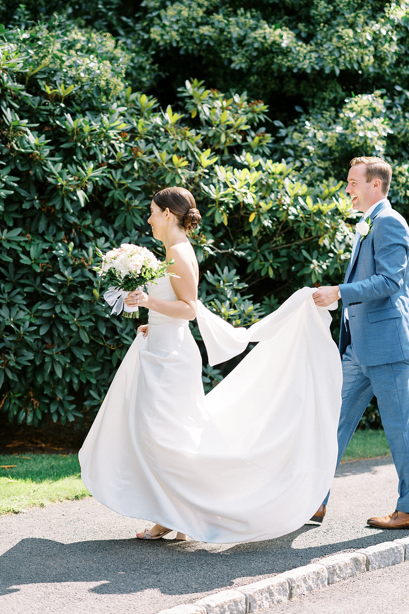 man carries train of dress by Cape Cod wedding photographer