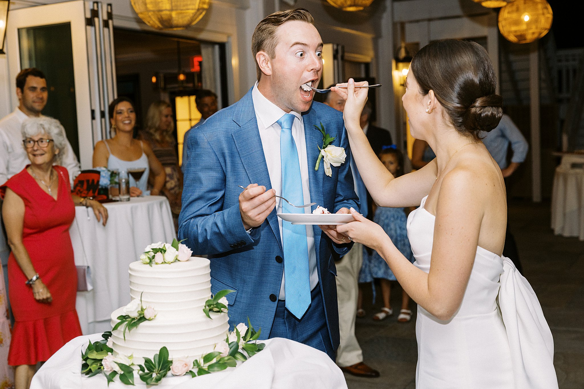 groom has surprised look as bride feeds him cake at Field Club of Greenwich 