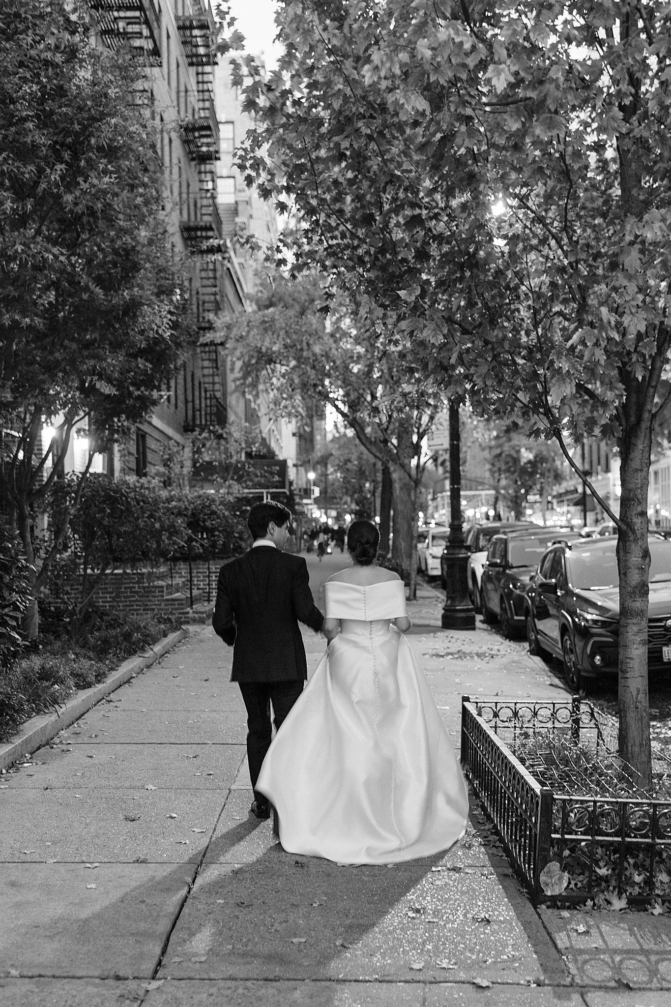 couple walks hand in hand down street by NYC wedding photographer 