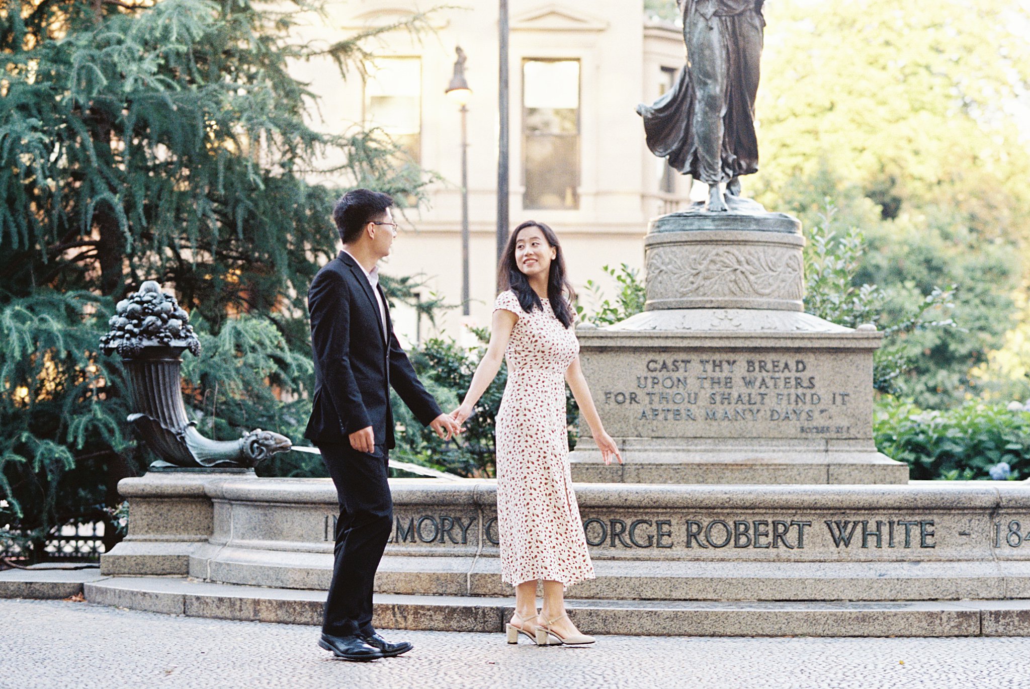 woman looks back at partner as they walk in front of statue by Lynne Reznick Photography