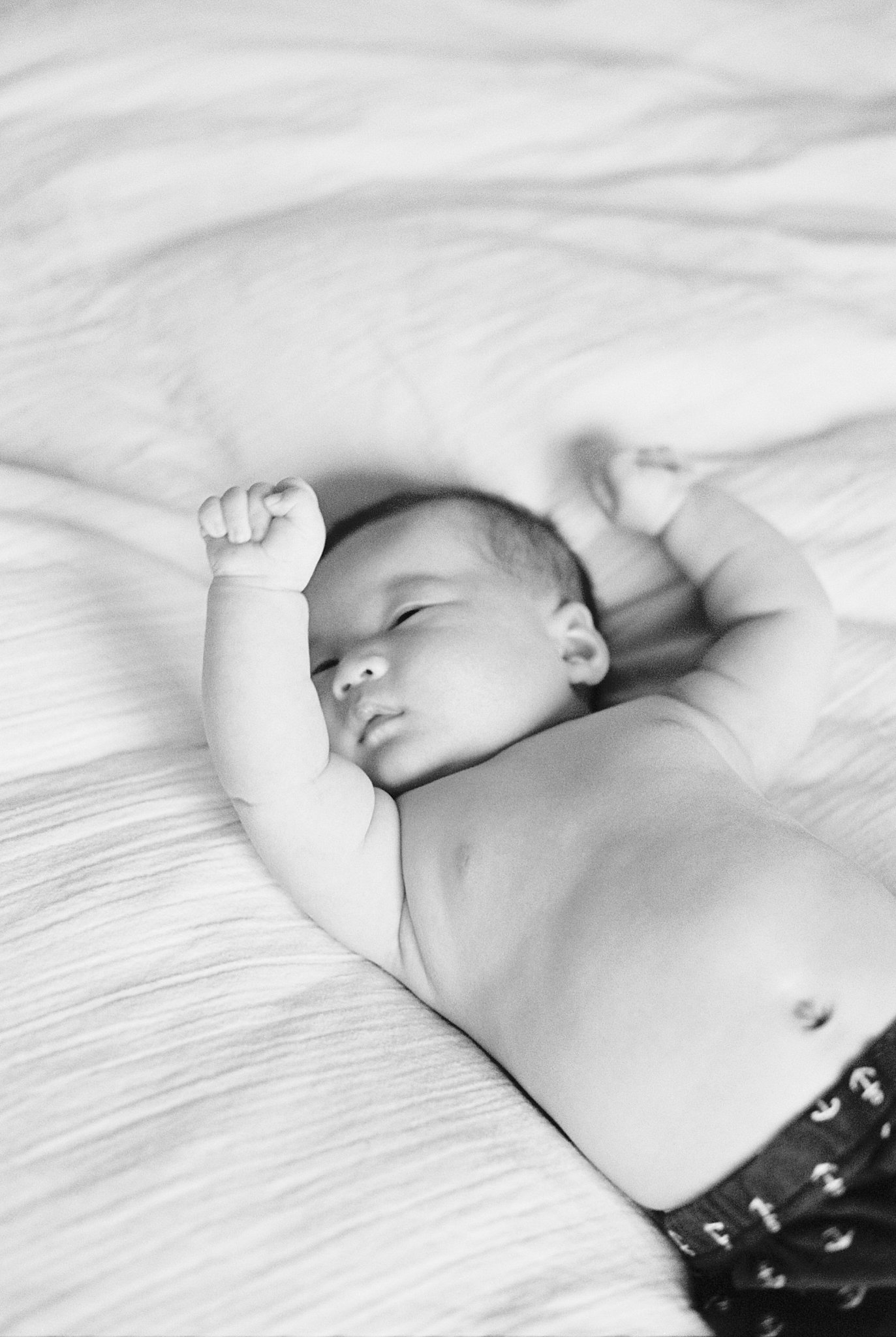 baby puts arms in the air as he lays down by Boston family portrait photographer