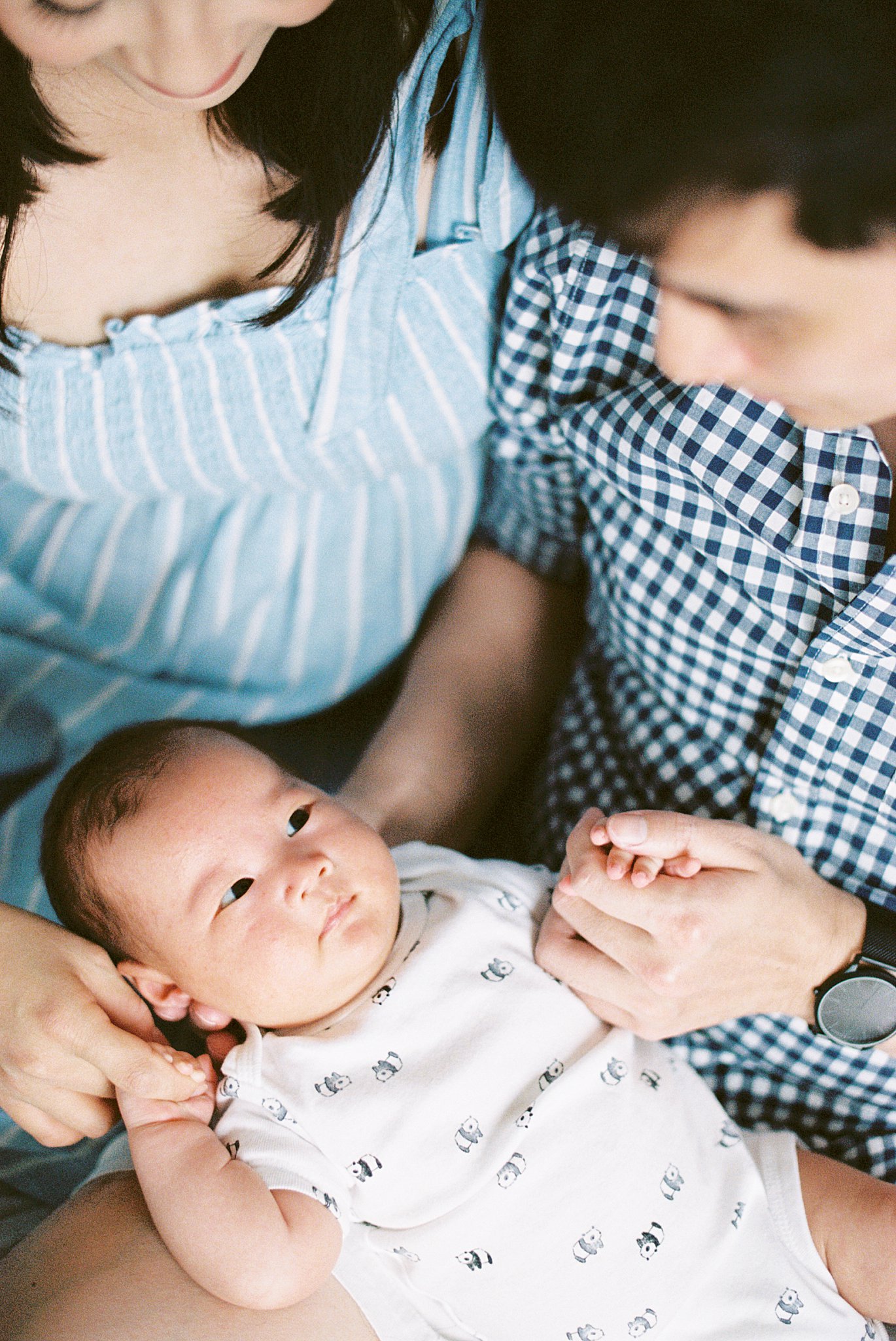 father holds son's hand as he looks at him during in-home lifestyle session