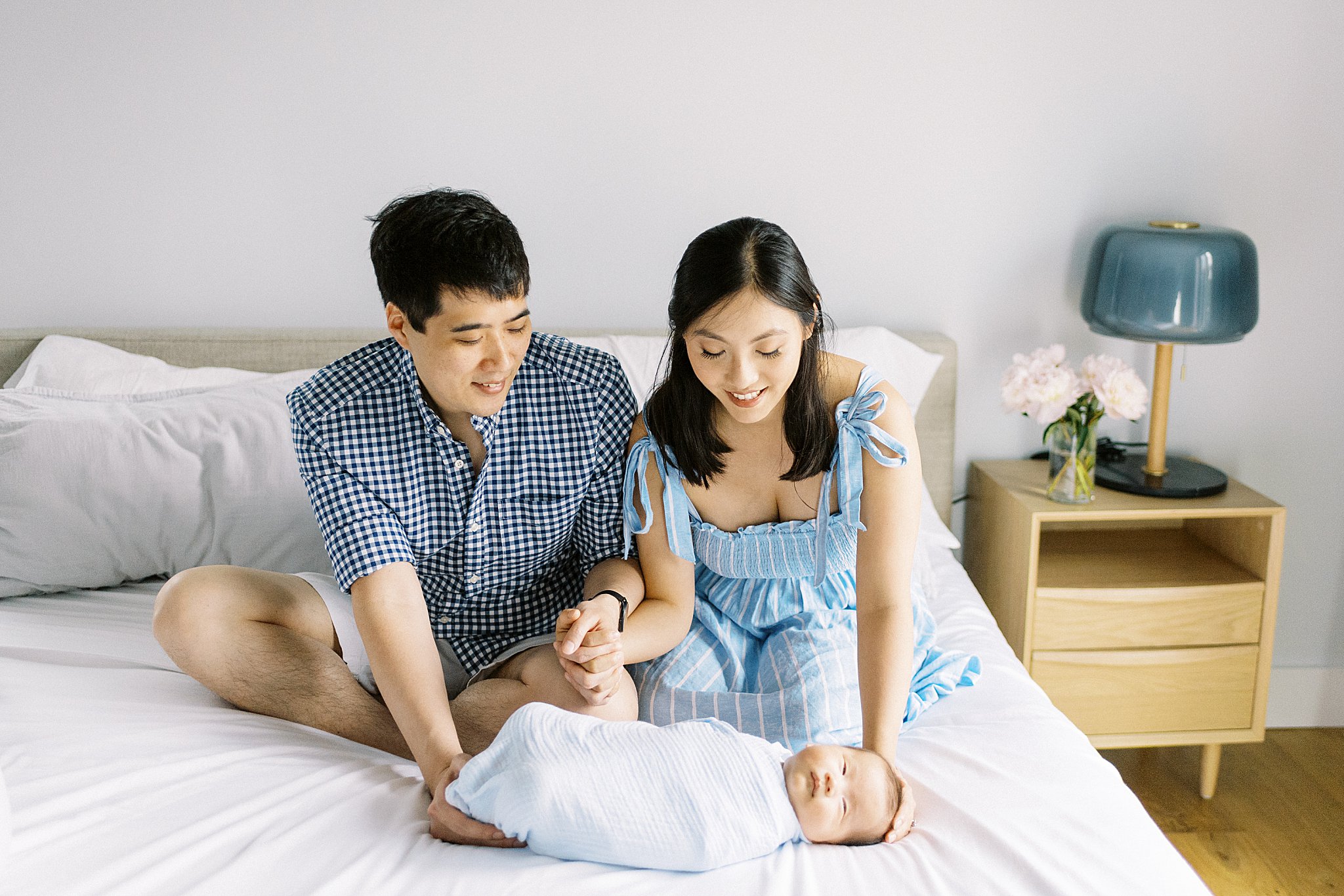 parents smile as they look at their swaddled baby by Boston family portrait photographer