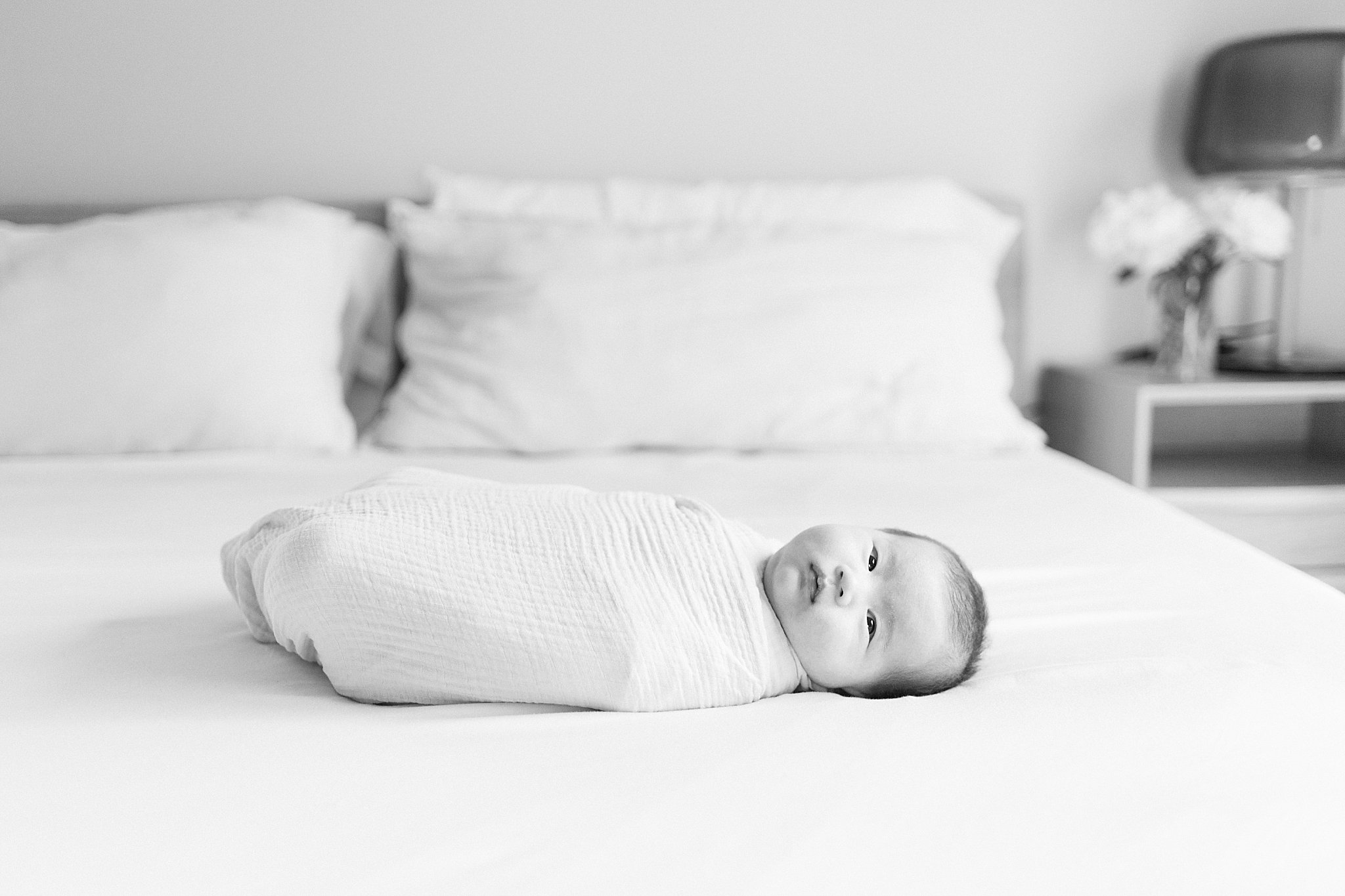 baby lays on bed looking straight during in-home lifestyle session