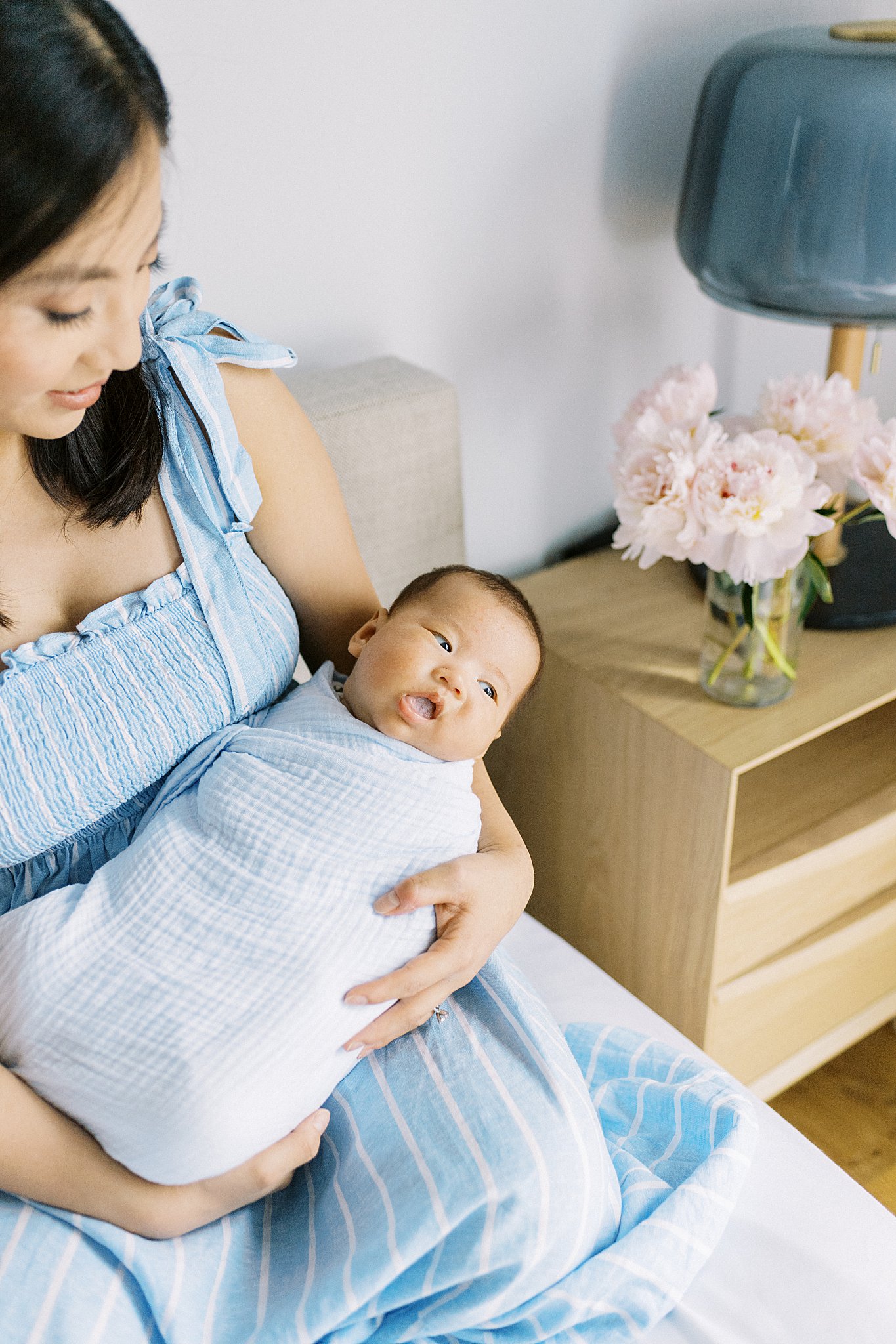 baby looks off to the side while his mom holds him by Lynne Reznick Photography