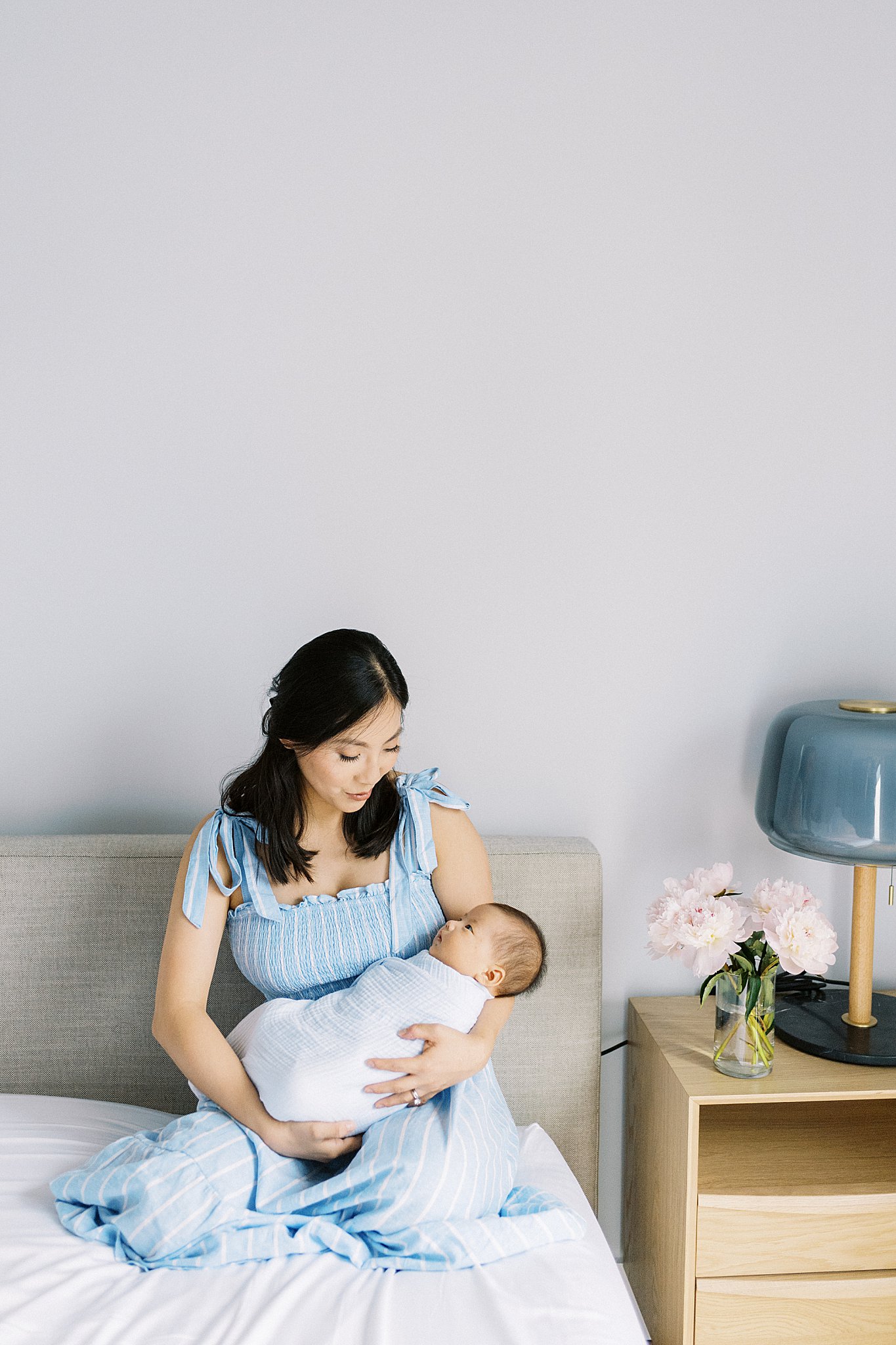 mother holds son as she sits in her bed at in-home lifestyle session