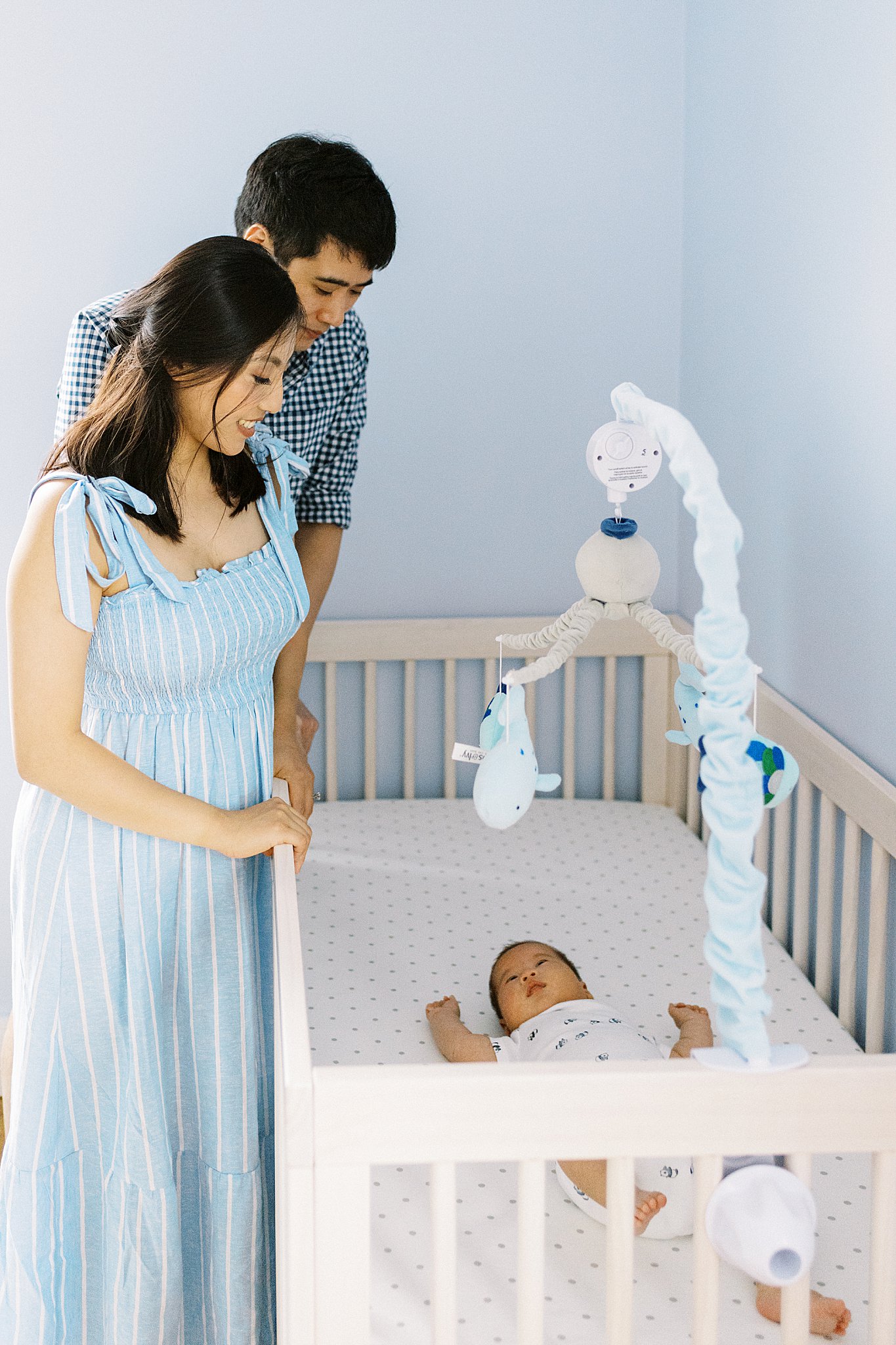 parents look at son in his crib by Boston family portrait photographer