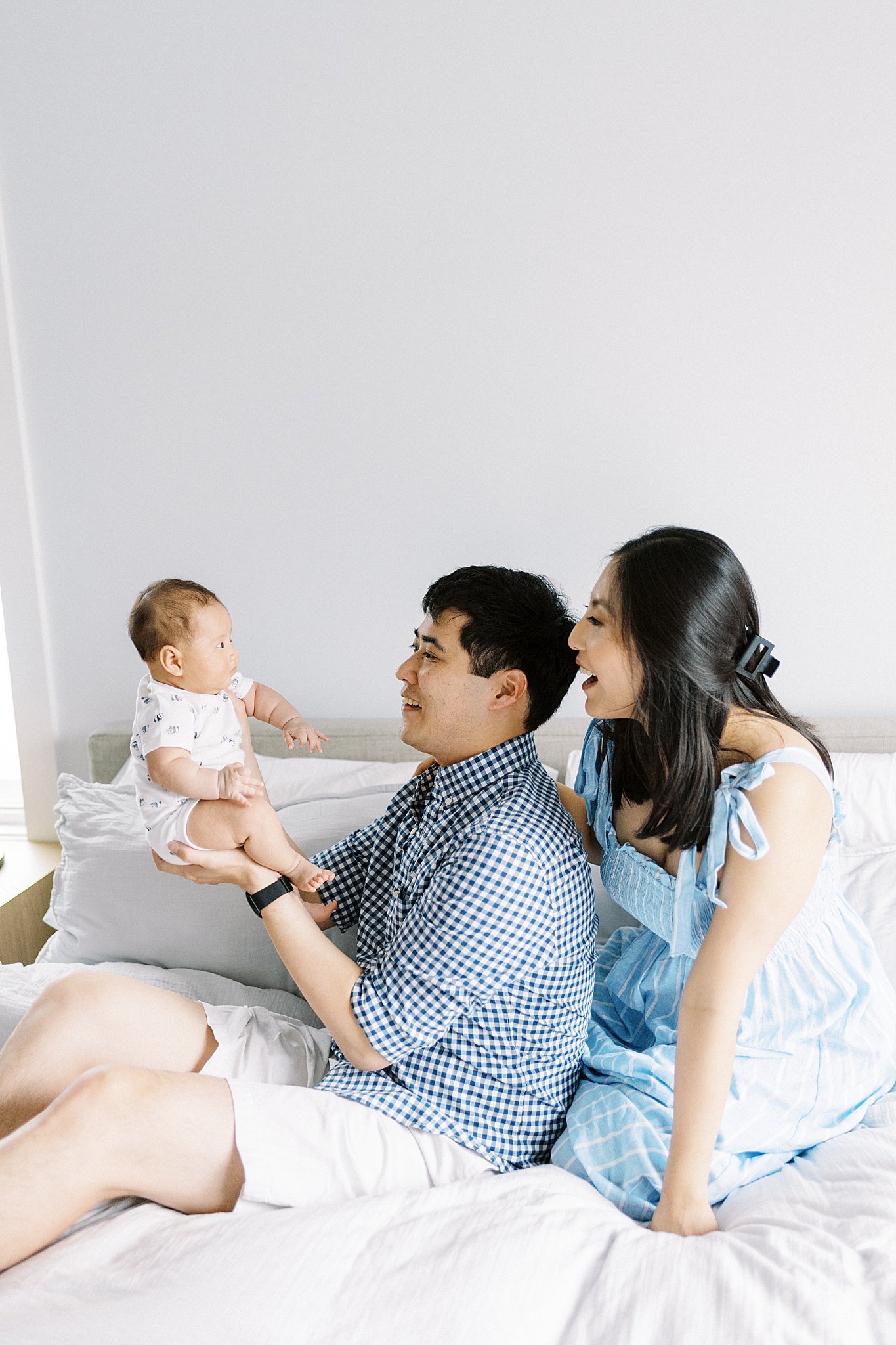 man holds up baby as parents smile at him by Lynne Reznick Photography