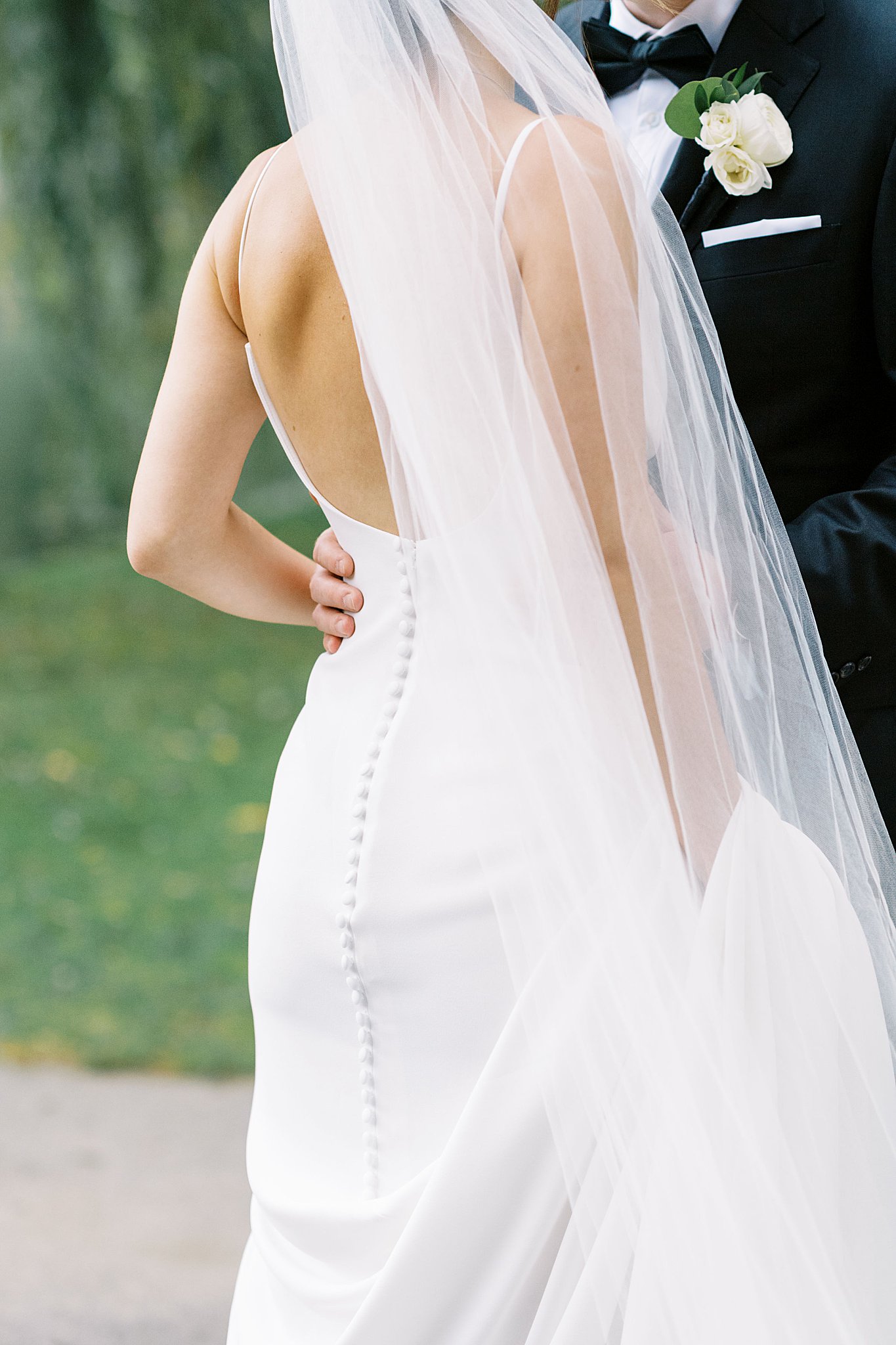 man puts hand on woman's waist as her veil blows in wind before Museum of Science ceremony