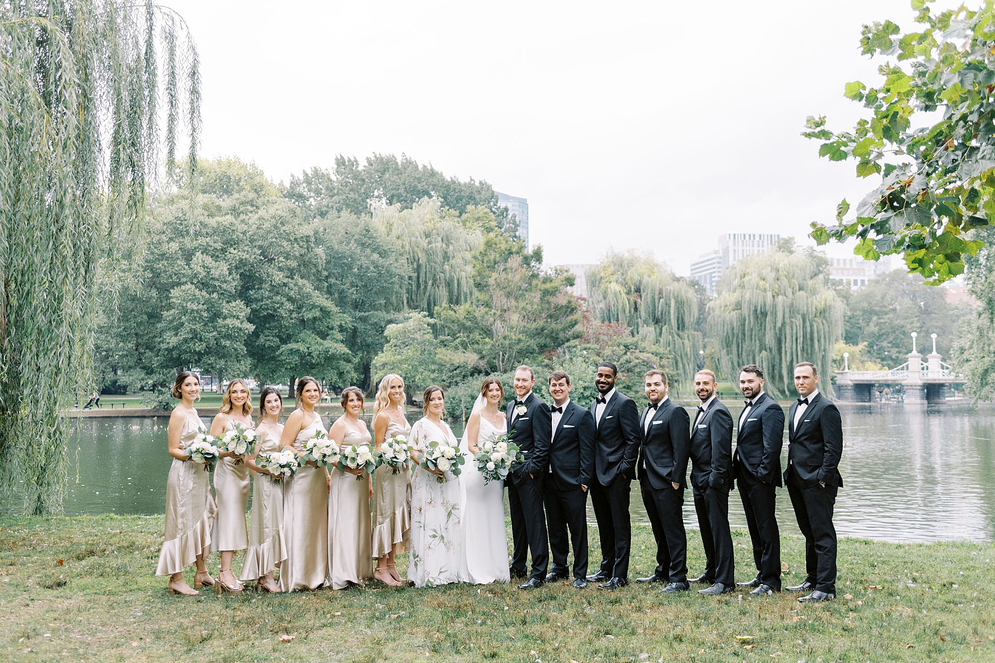 wedding party smiles in front of lake at park before Museum of Science ceremony