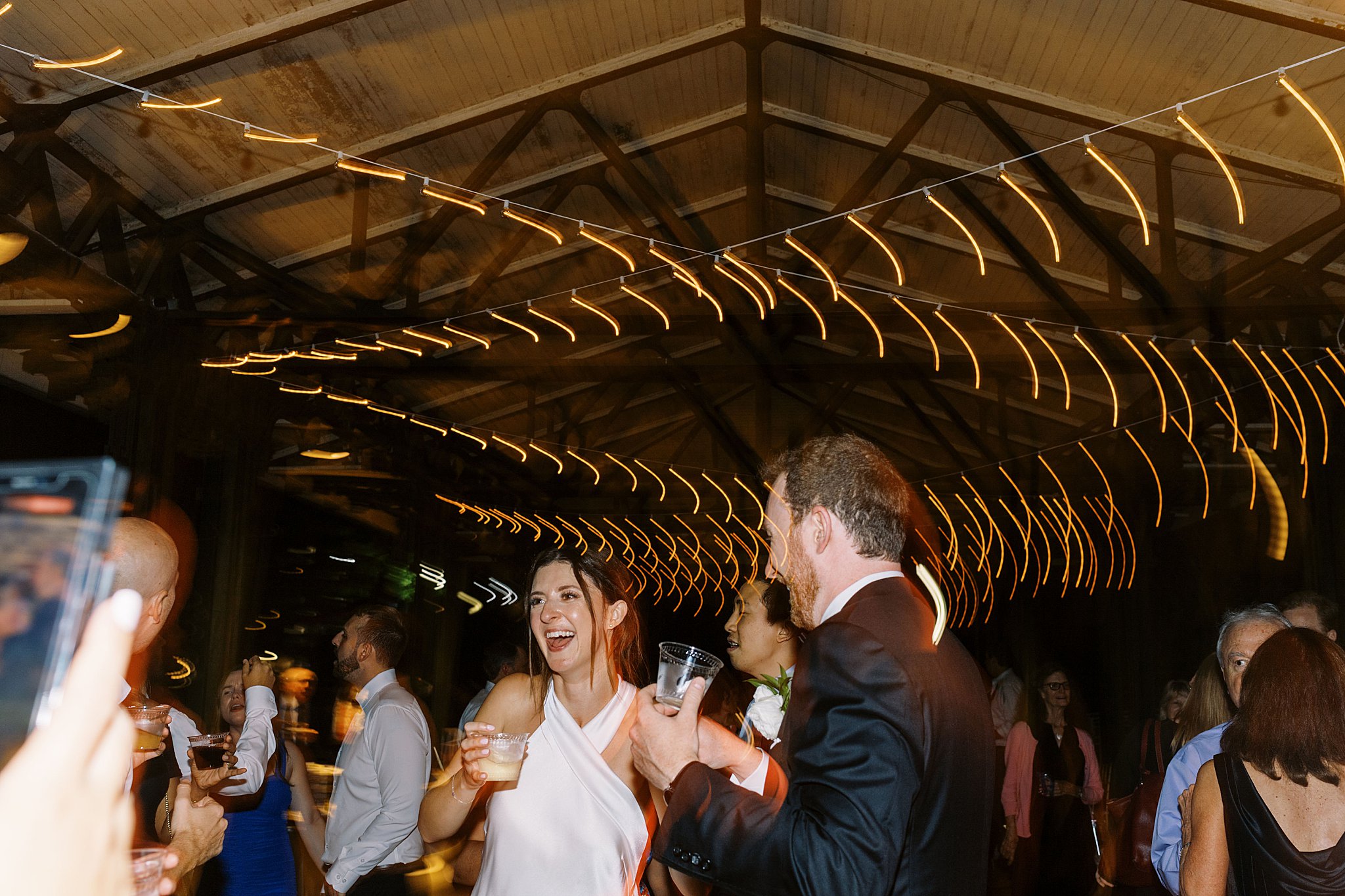 bride and groom dance together holding drinks by Lynne Reznick Photography