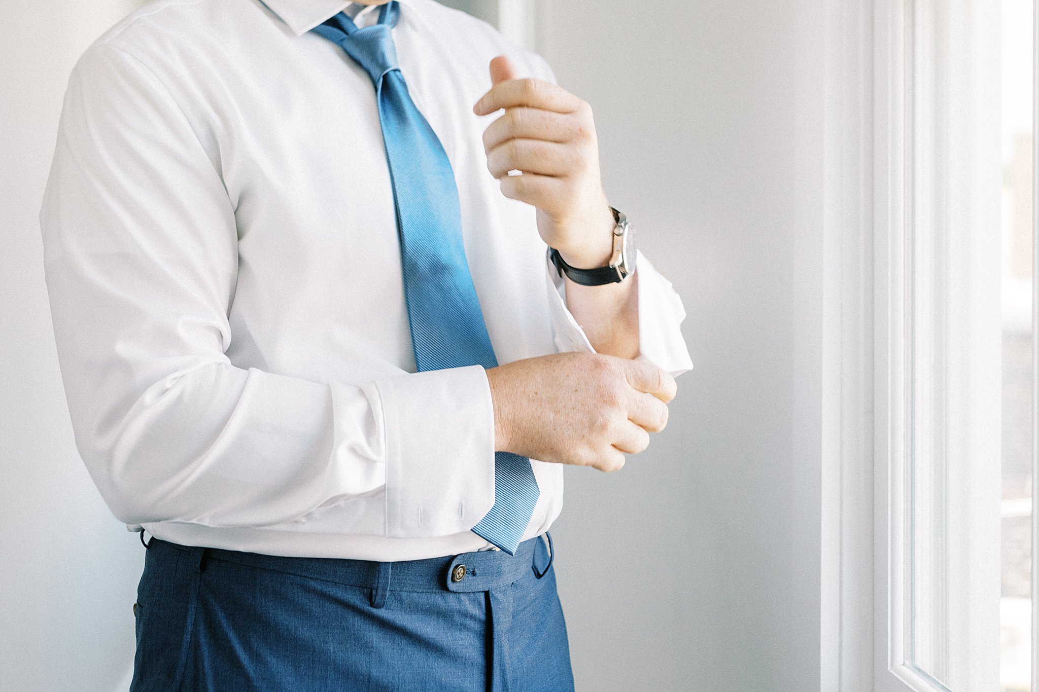 groom adjusts his cufflinks while getting ready by Boston wedding photographer