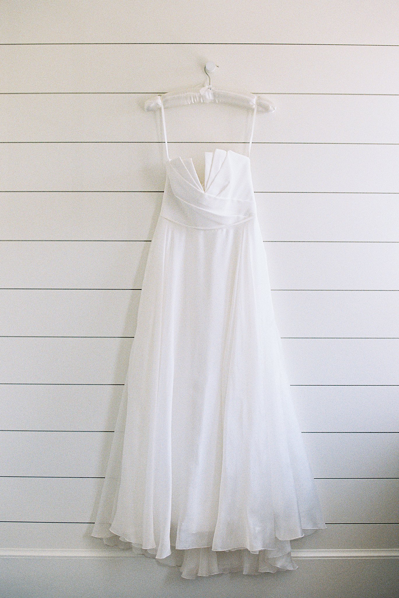 bridal gown hangs on shiplap wall by Boston wedding photographer