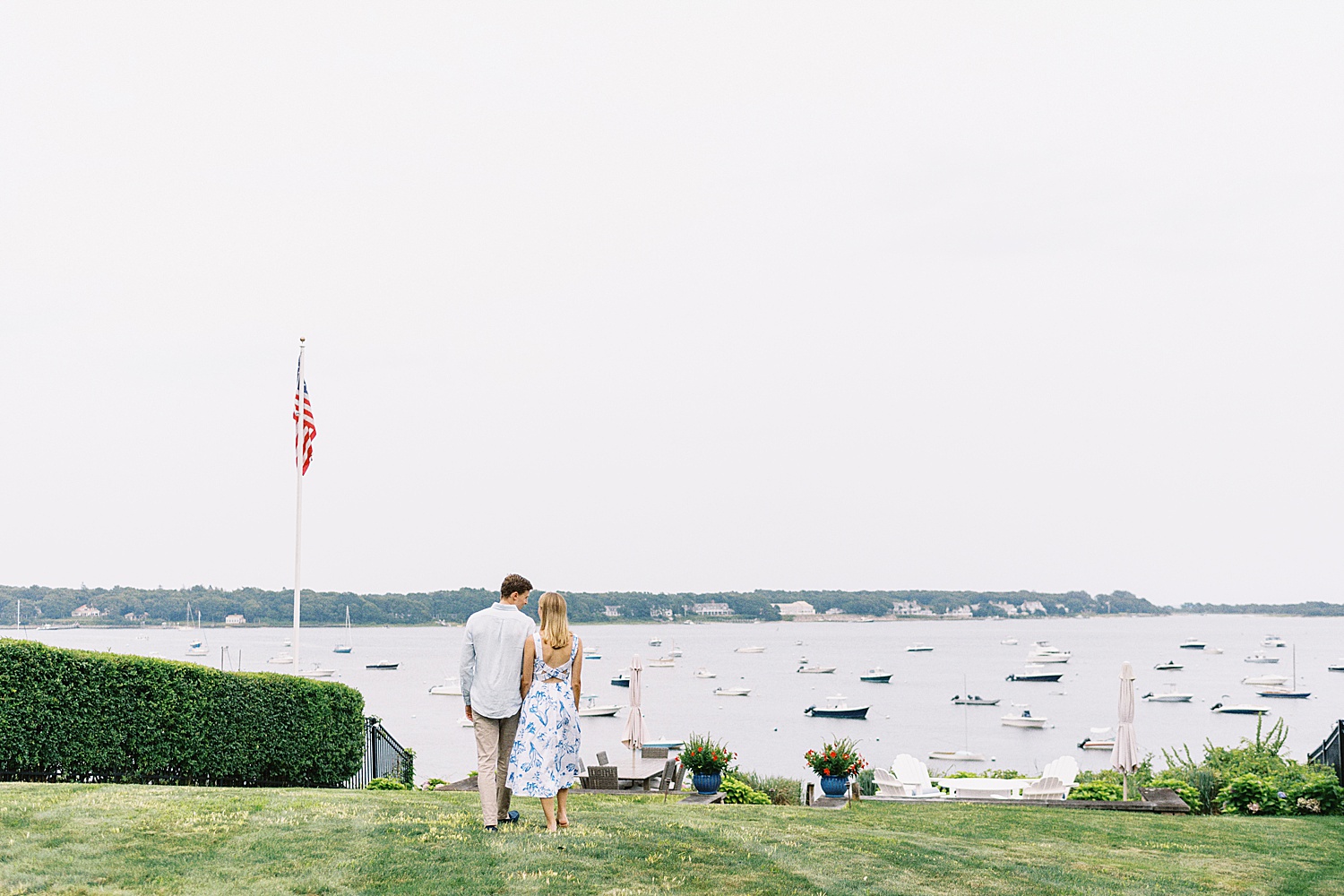 man and woman in blue walk towards water by Lynne Reznick Photography