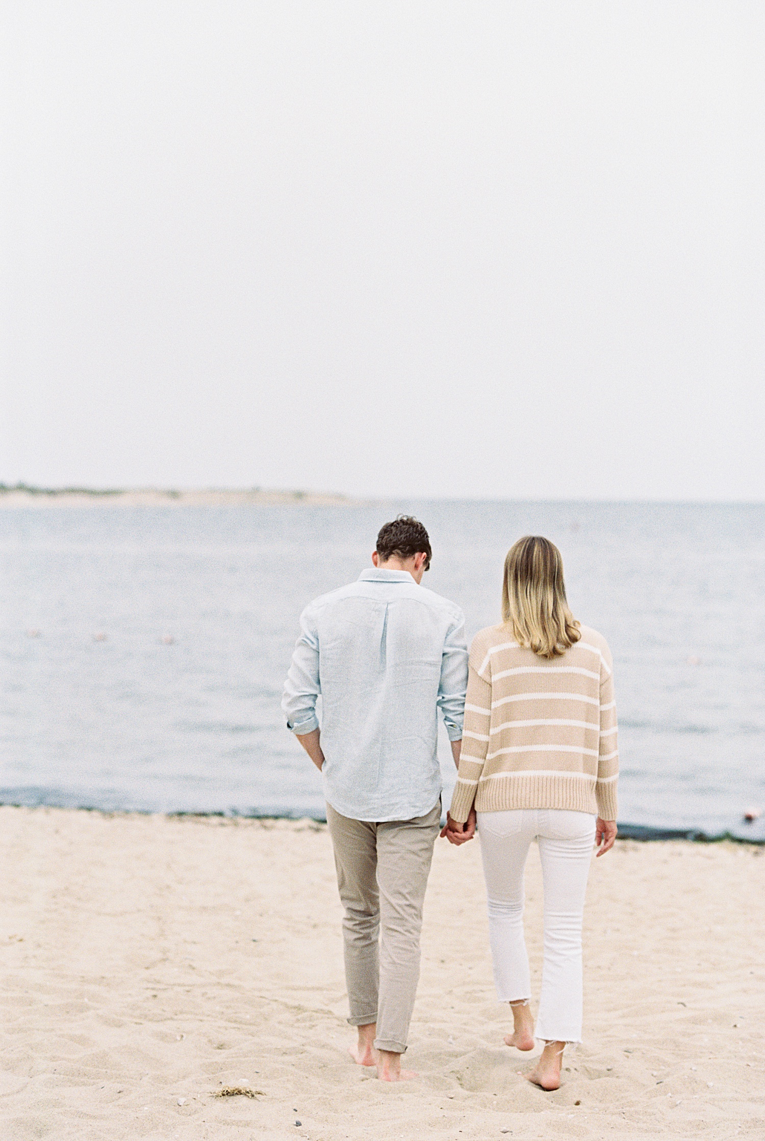 husband and wife-to-be stroll on the beach at sunset on Cotuit Bay by Lynne Reznick Photography