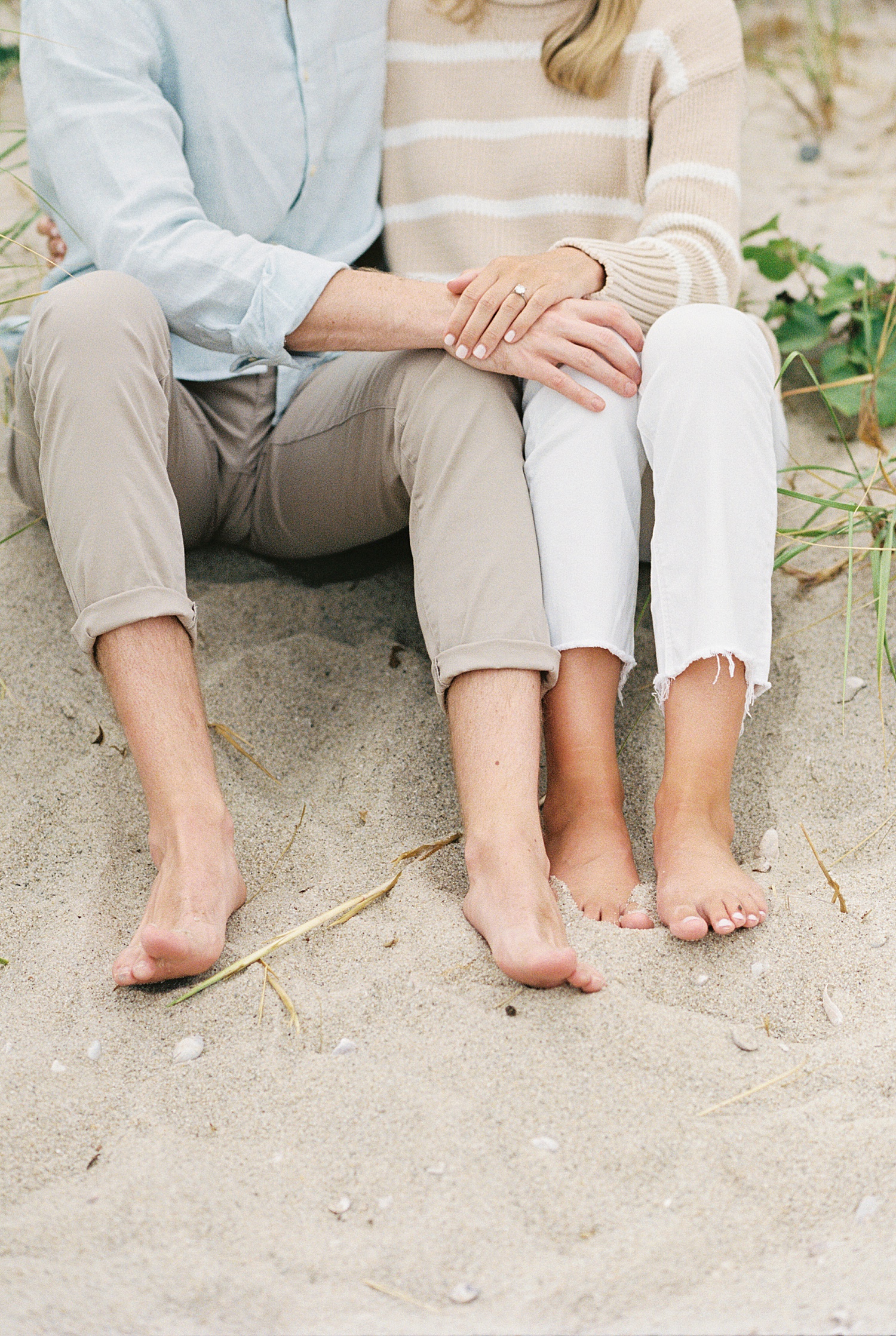 engaged couple stick their feet in the sand at their Cotuit Bay session