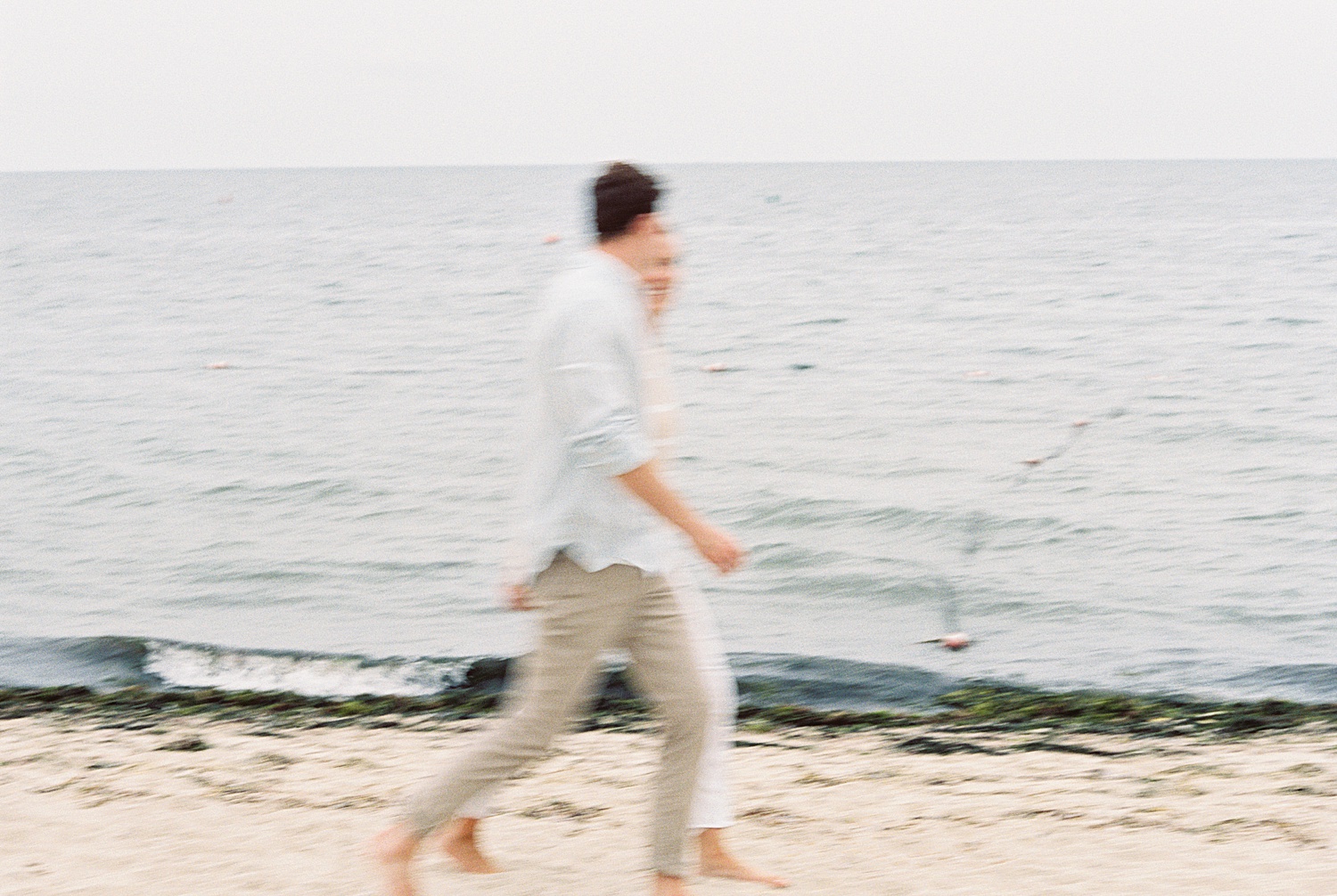 two people running on the beach in the overcast evening light by Cape Cod Wedding Photographer