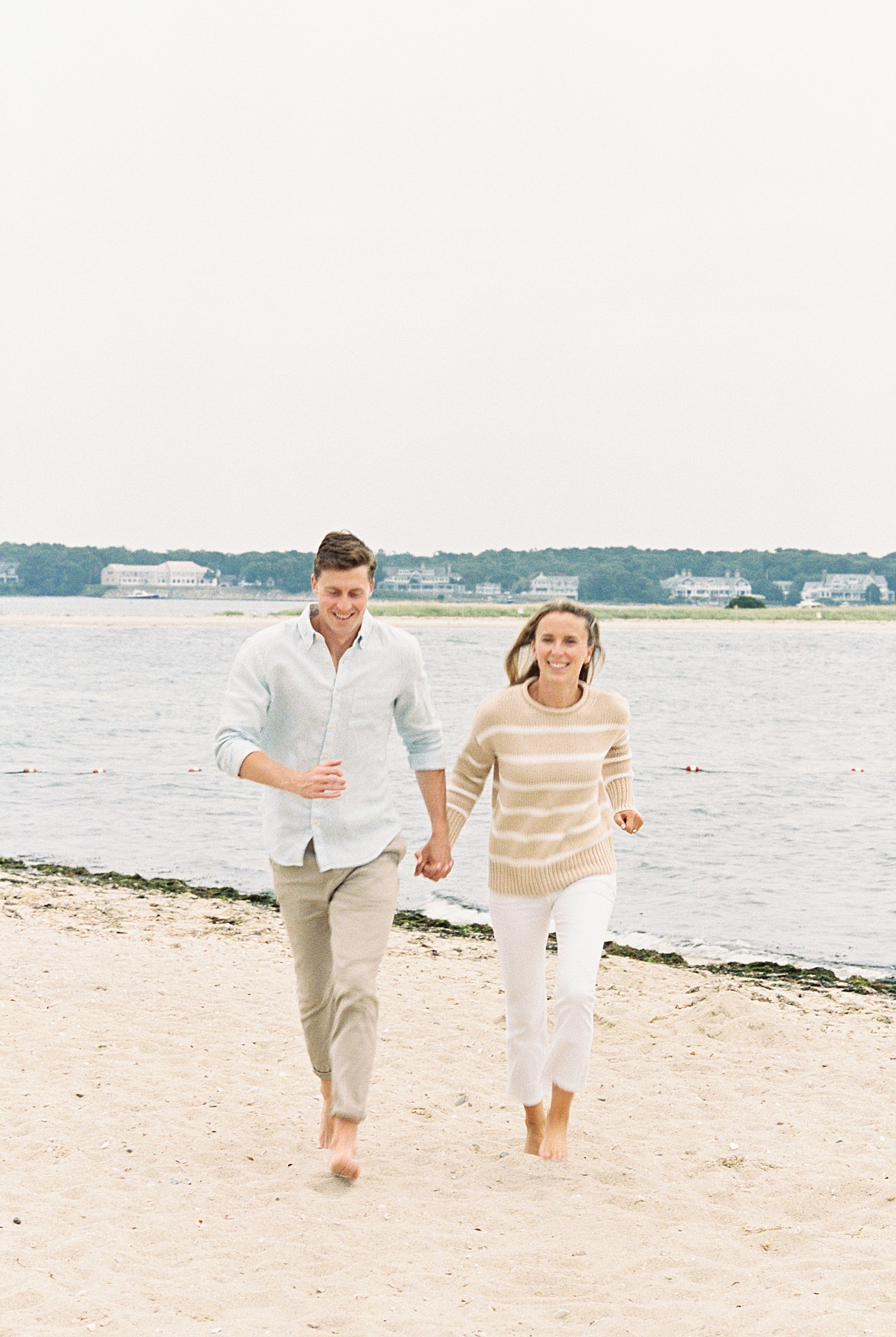 man and woman run on the beach at Cotuit Bay laughing together