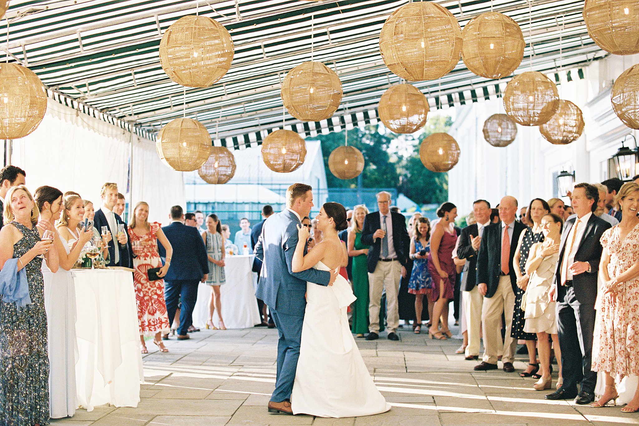 guests watch as bride and groom dance under lanterns by Lynne Reznick Photography